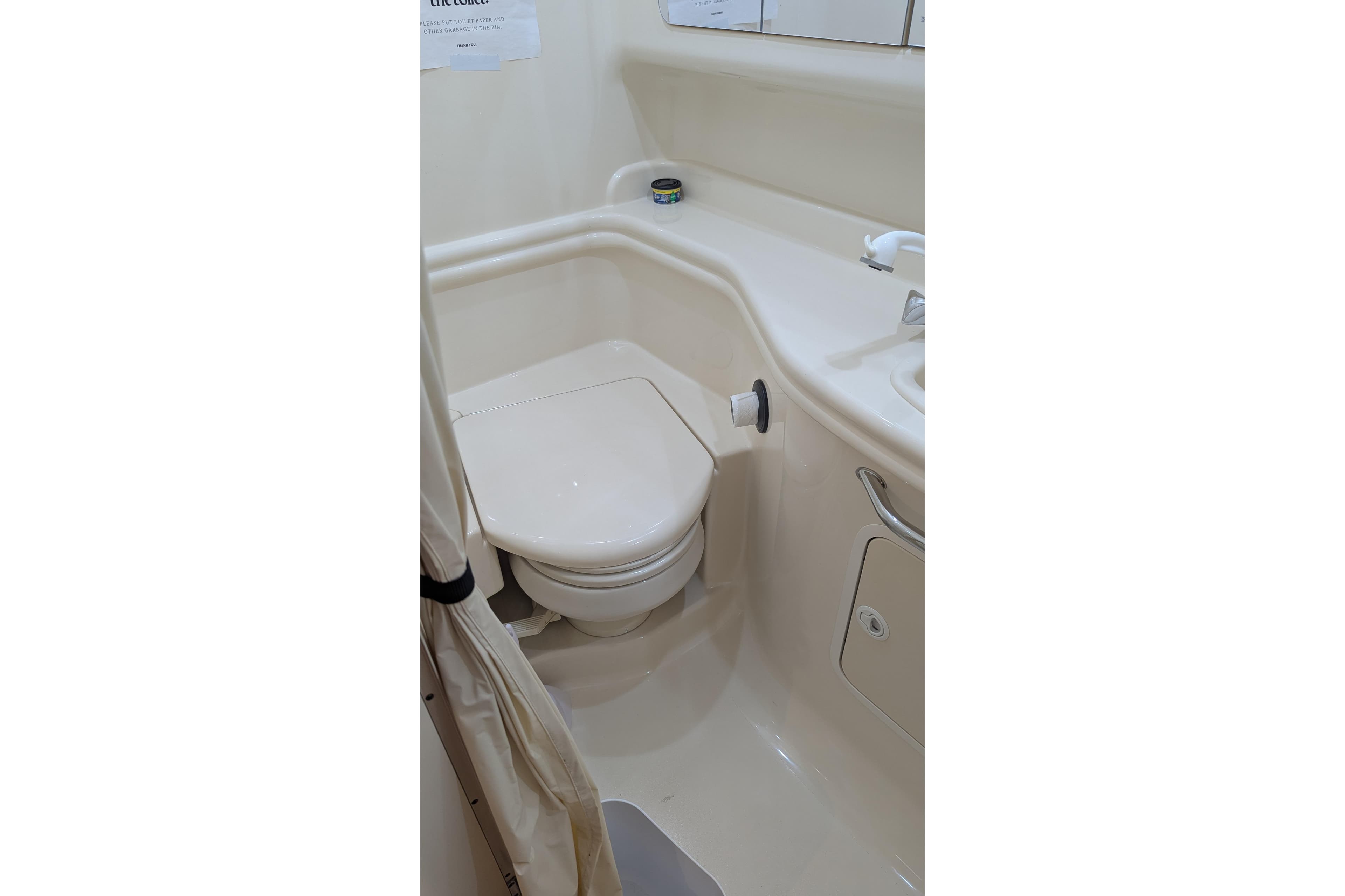 Bathroom interior of 2004 Sea Ray 340 Sundancer yacht, featuring compact toilet and sink.