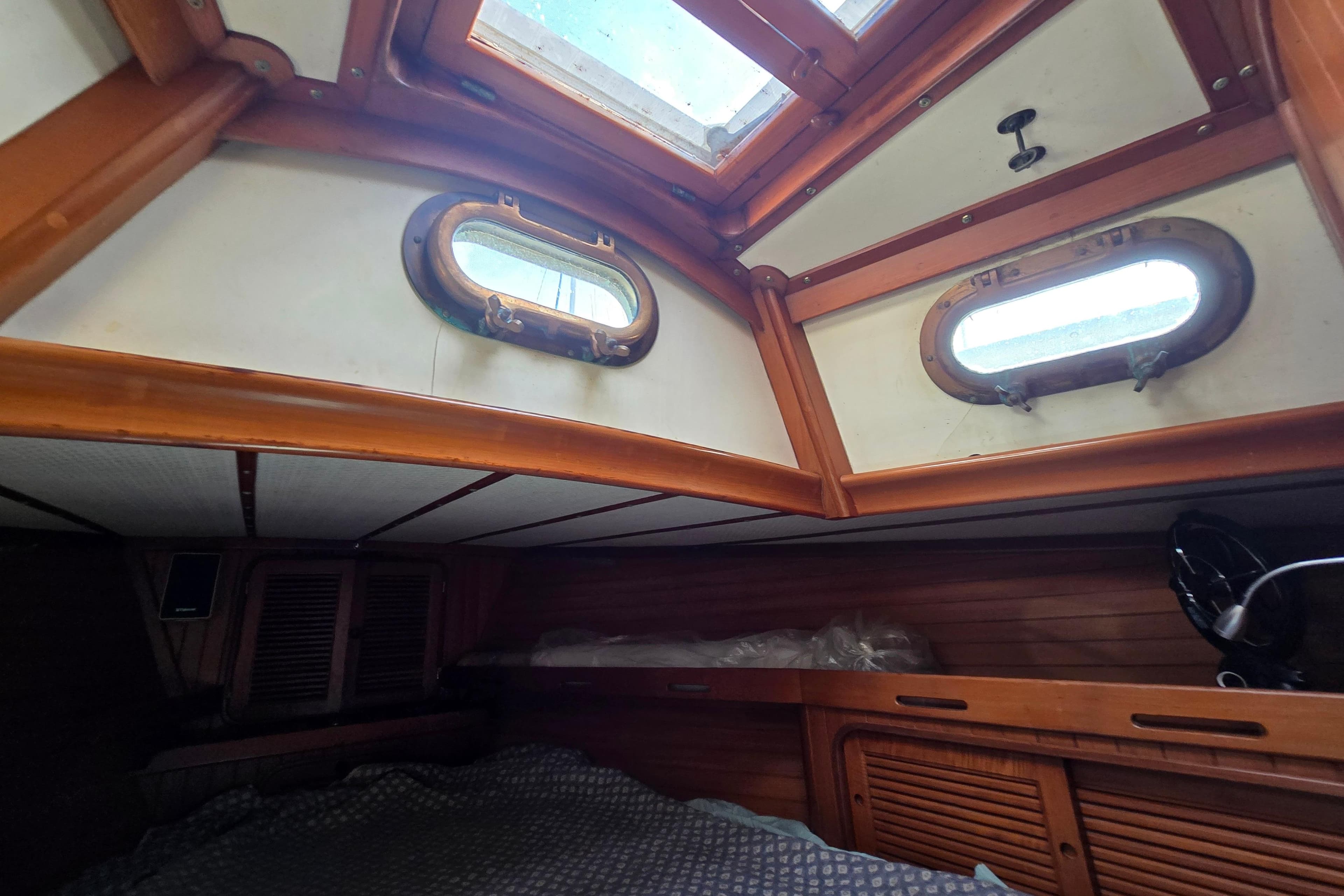 Interior cabin of a 1985 Baba 35 sailboat with wooden accents and portholes.