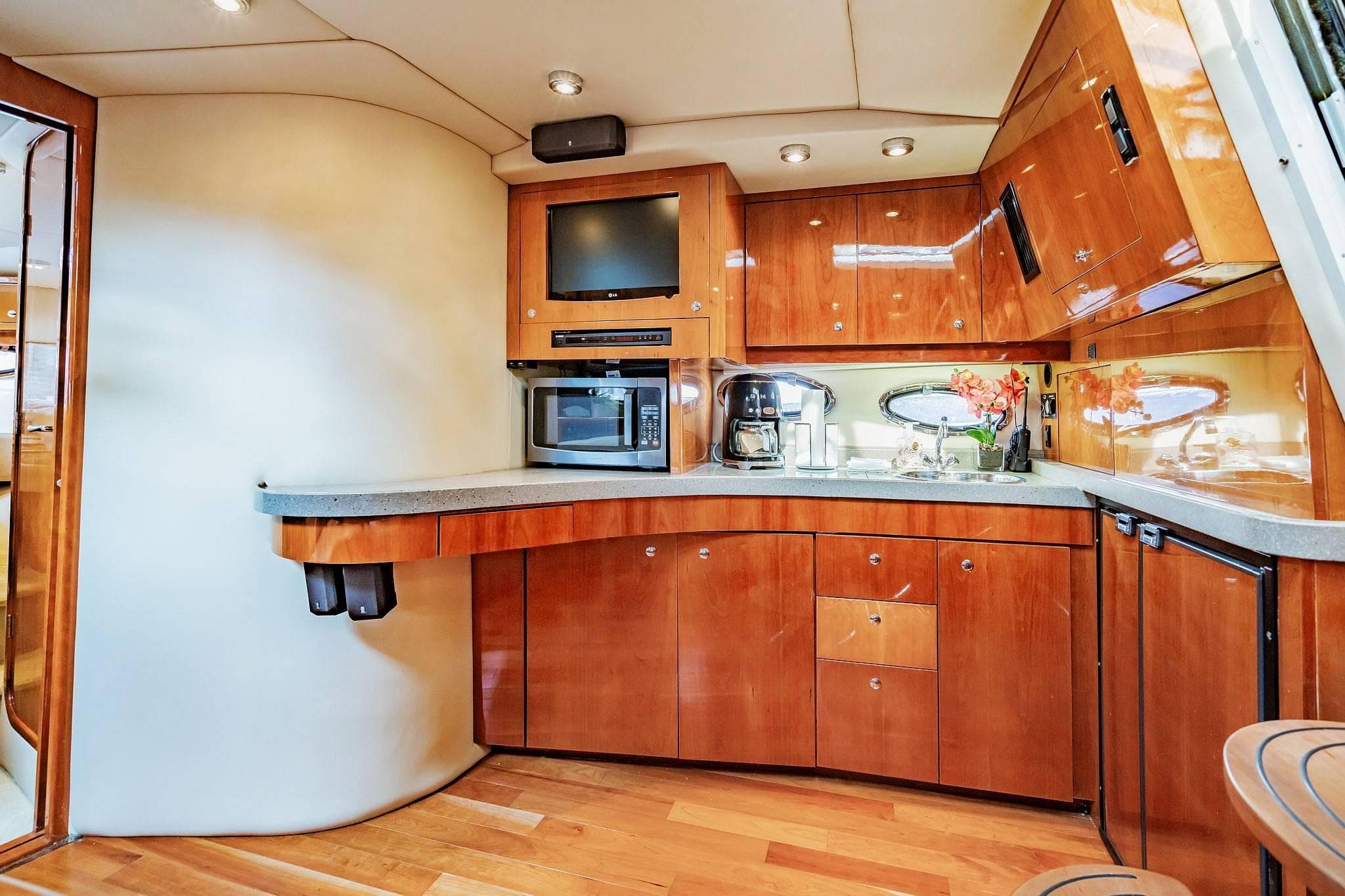 Luxurious 2010 Regal Commodore 4460 yacht kitchen with modern appliances and elegant wood cabinetry.