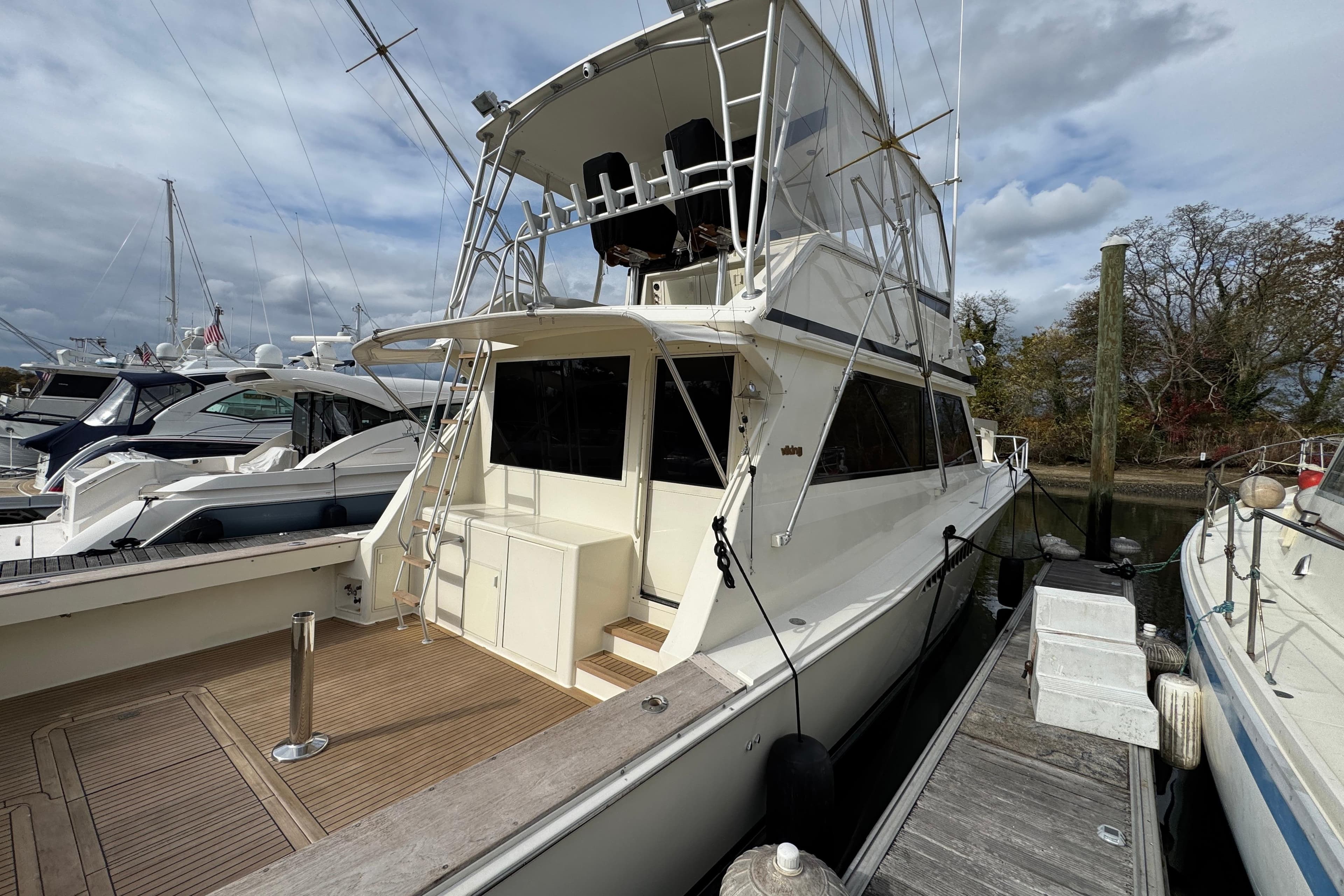 1991 Viking 53 Convertible yacht docked at marina under cloudy sky.