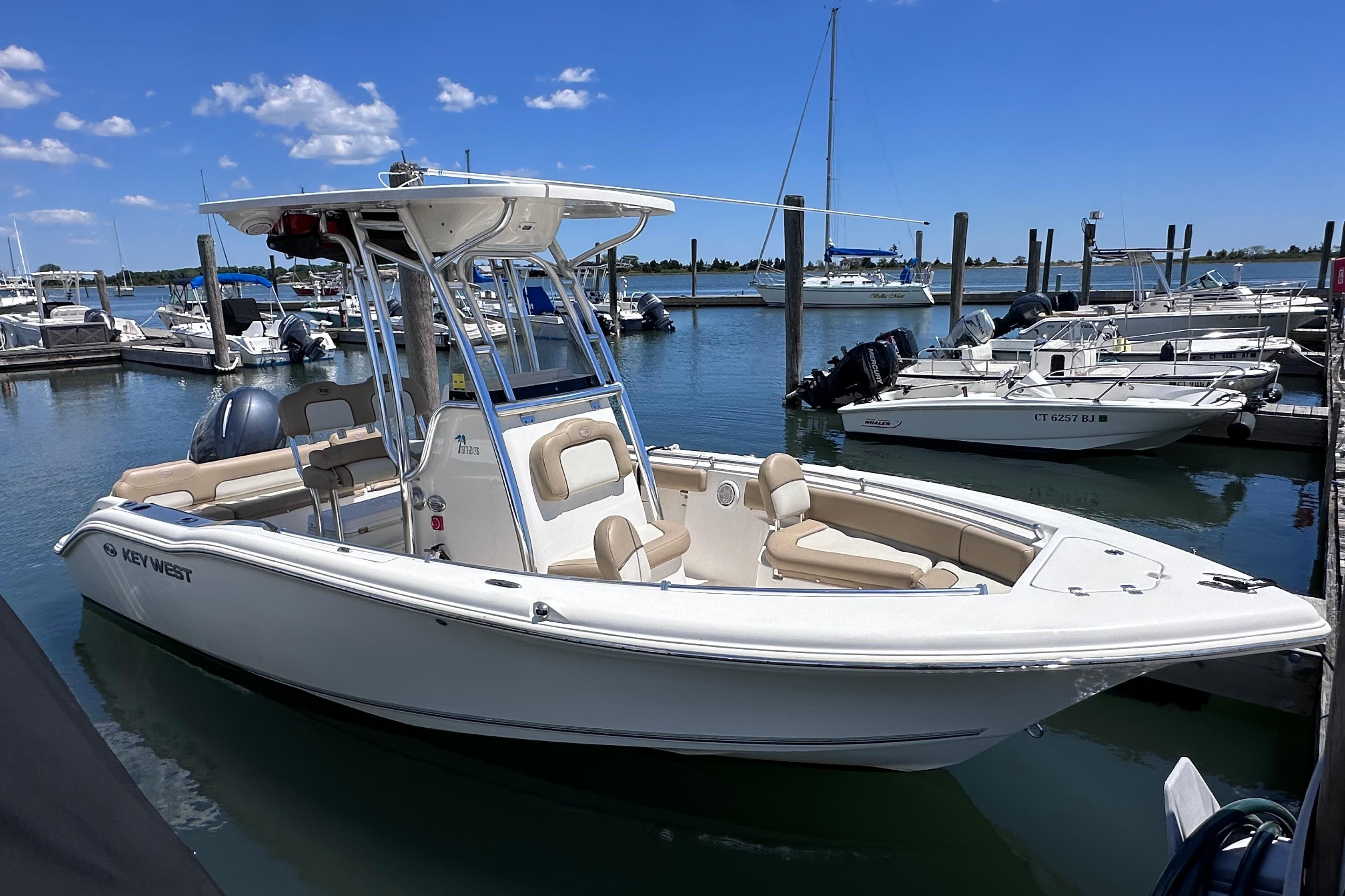 2019 Key West 219 FS boat docked at marina under clear blue sky.