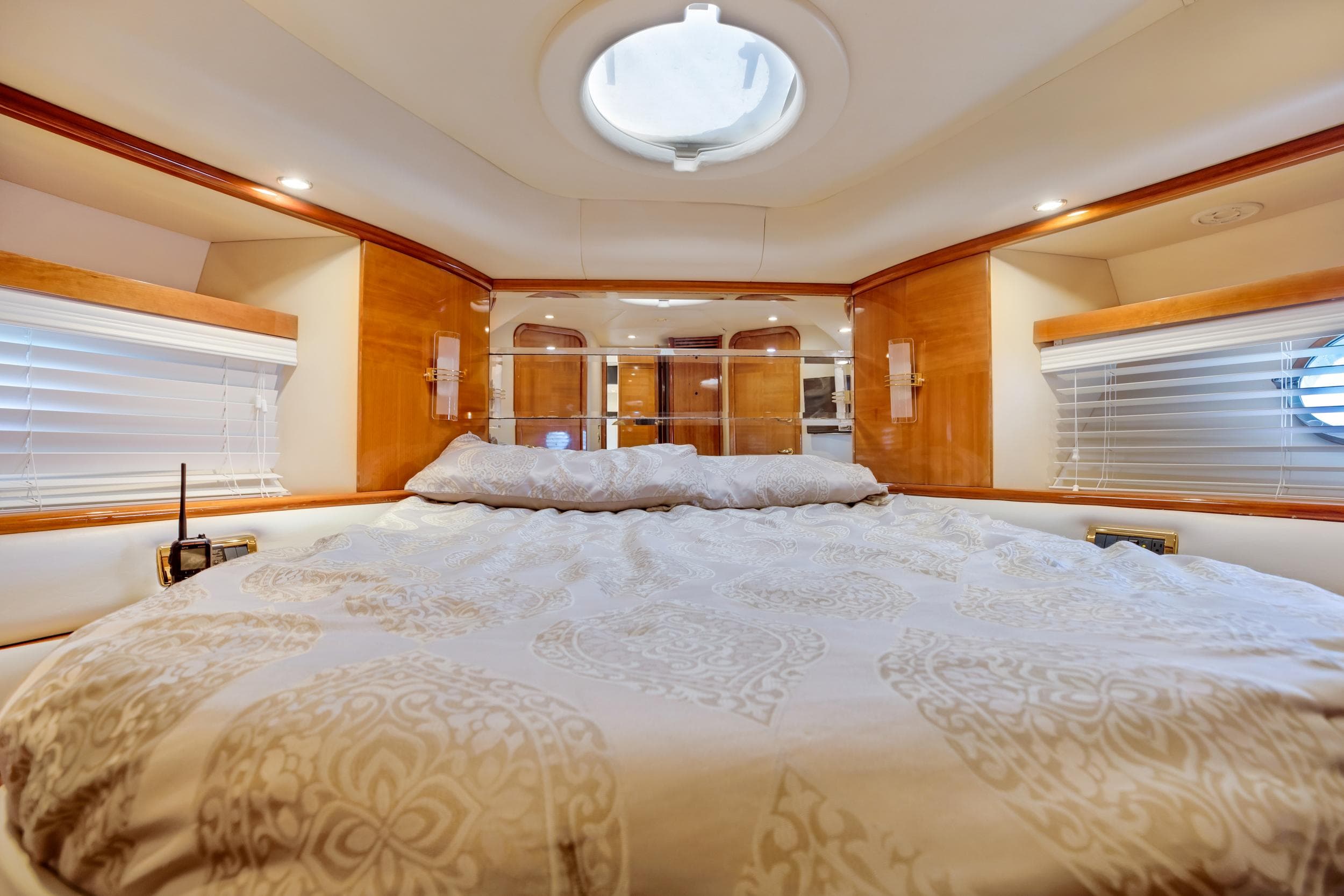 Luxurious bedroom interior of 2004 Azimut 62 yacht with elegant bedding and wood accents.
