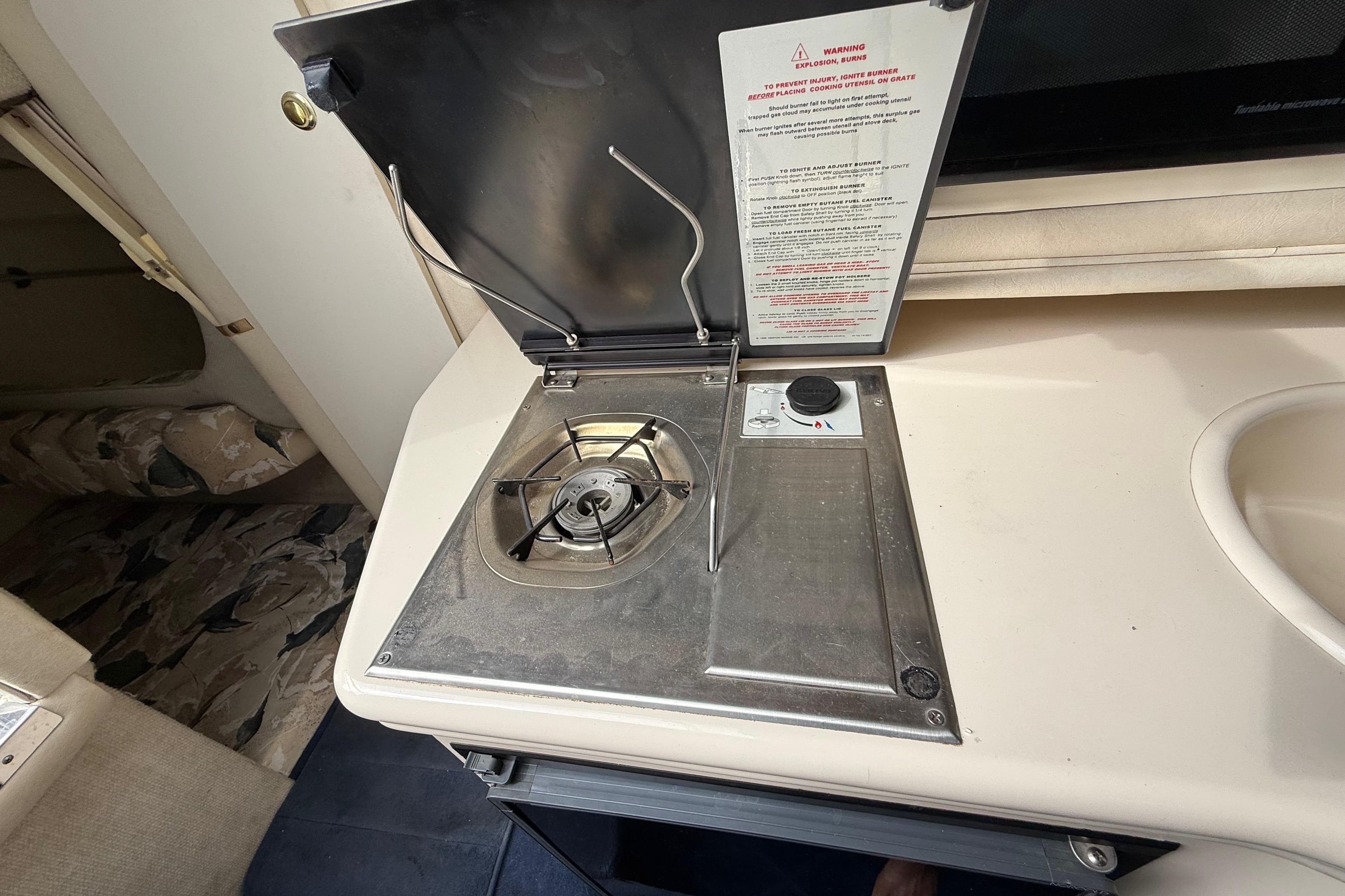 1999 Sea Ray Sundancer 260 interior stove and sink area, showcasing compact kitchen amenities.
