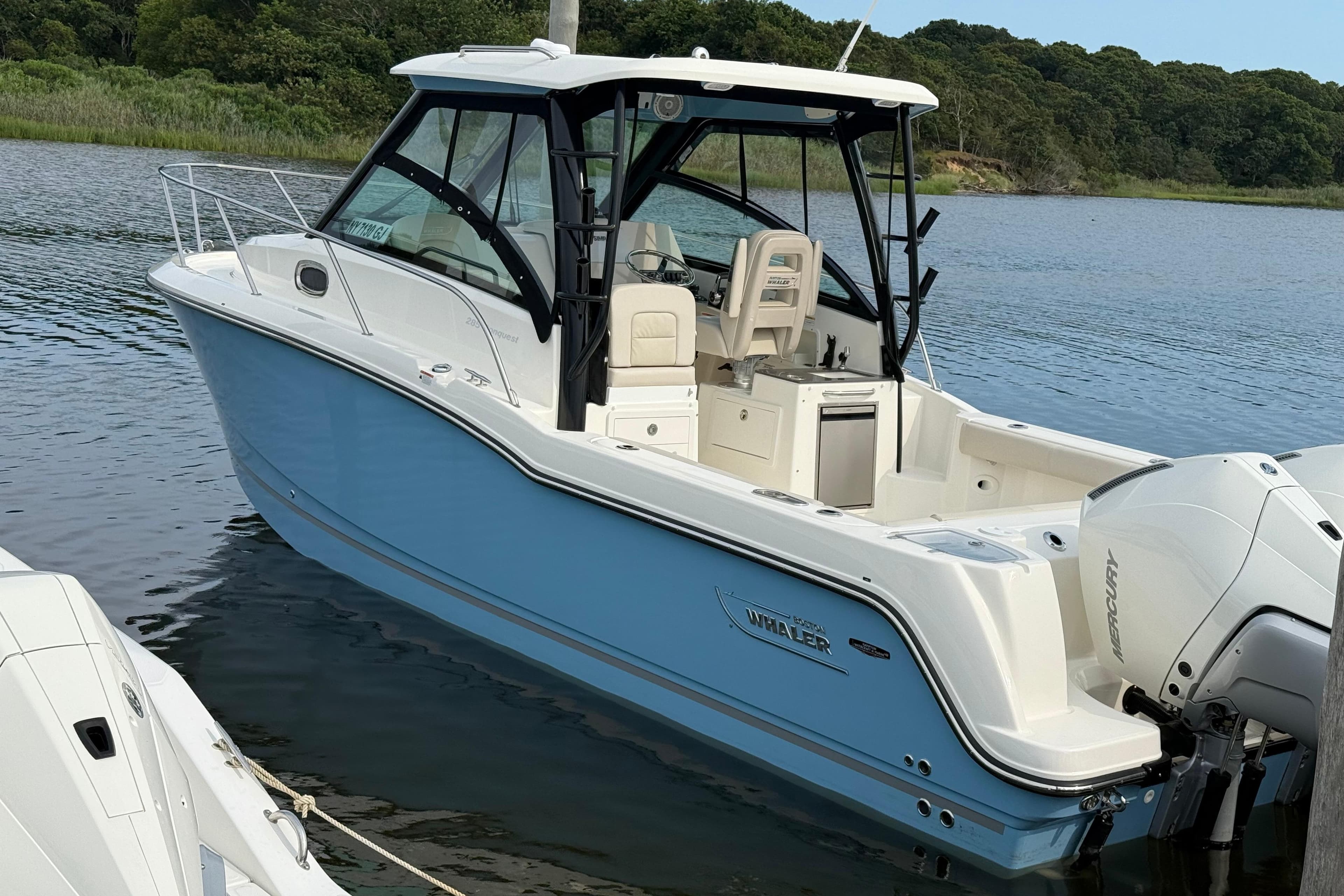 2026 Boston Whaler 285 Conquest boat docked on calm water, showcasing sleek design.