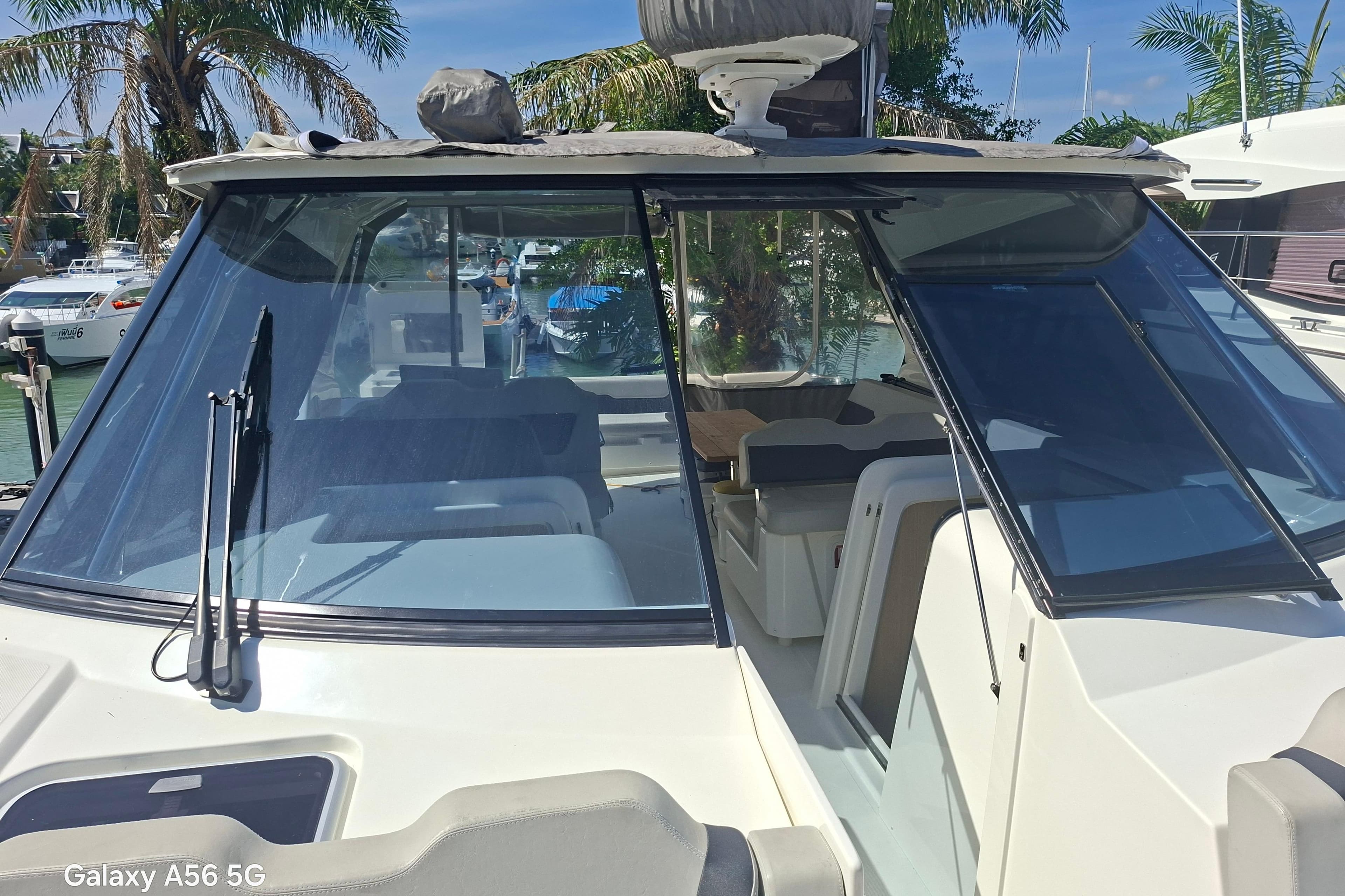 2021 Aquila 36 Sport boat with sleek windshield, docked near palm trees.