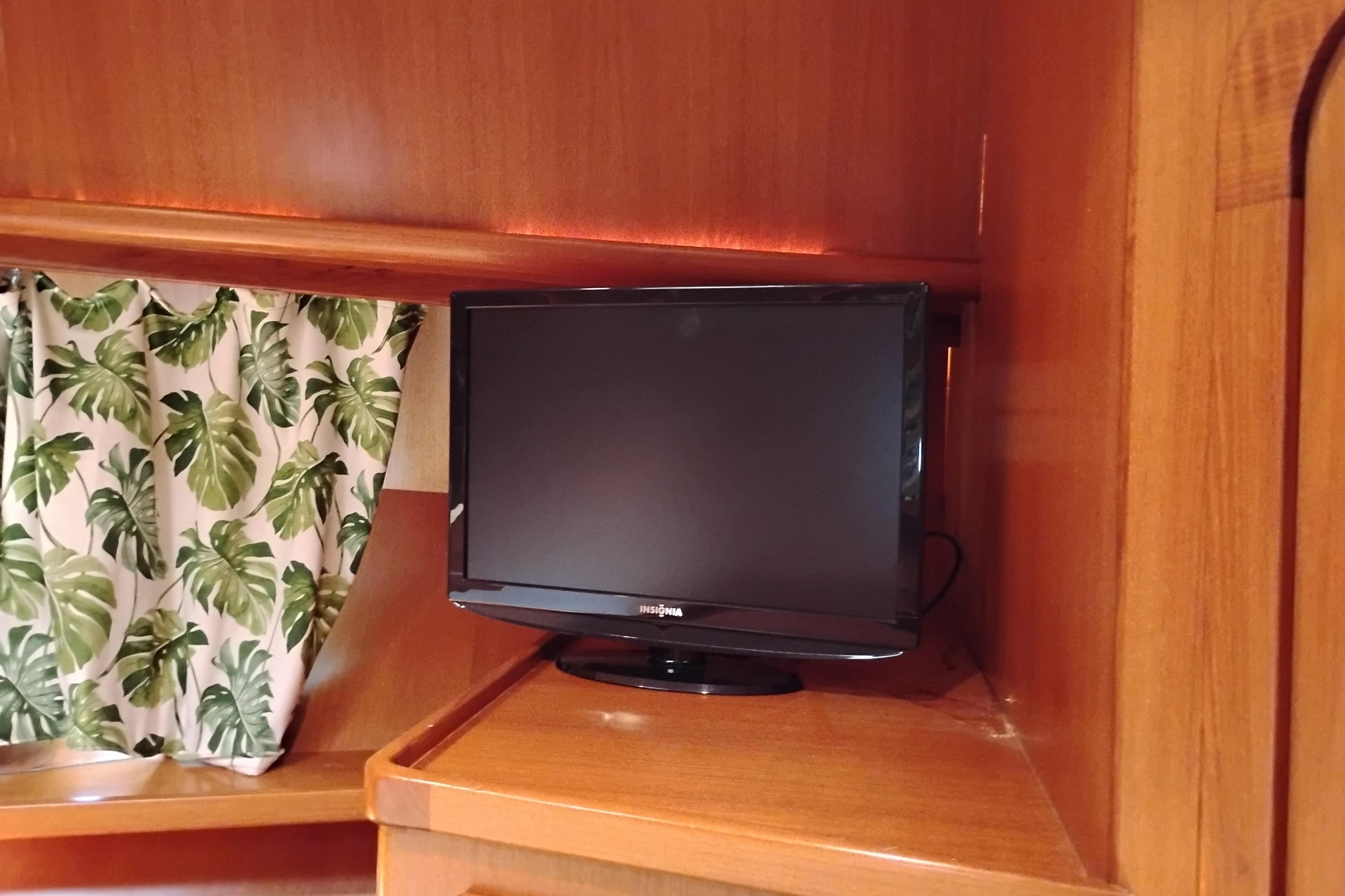 Small TV in wooden interior of 1997 Symbol 50 Pilothouse boat, with leafy curtain.