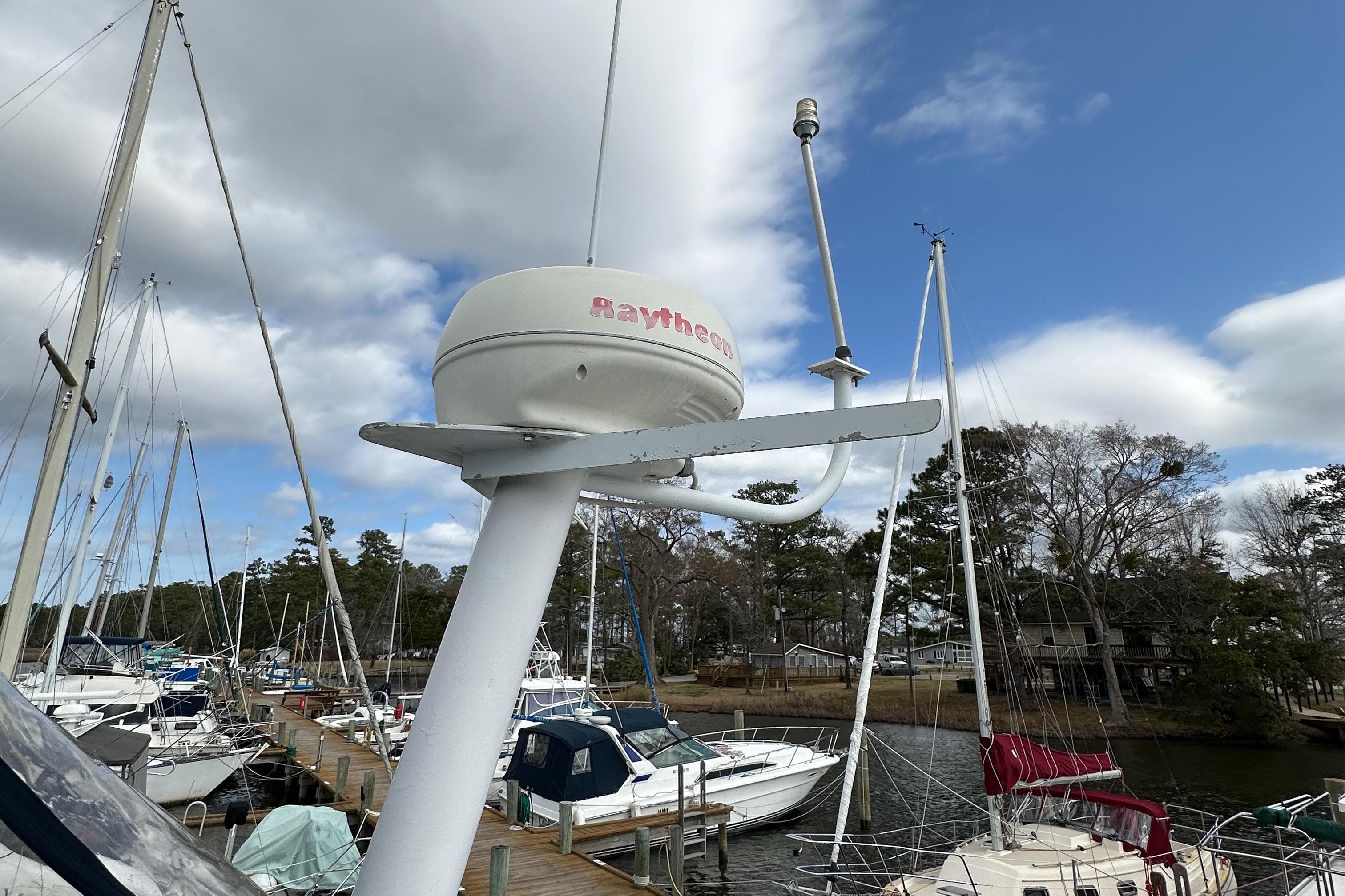 1998 Mainship 350 Trawler docked, featuring Raytheon radar, surrounded by sailboats under cloudy sky.
