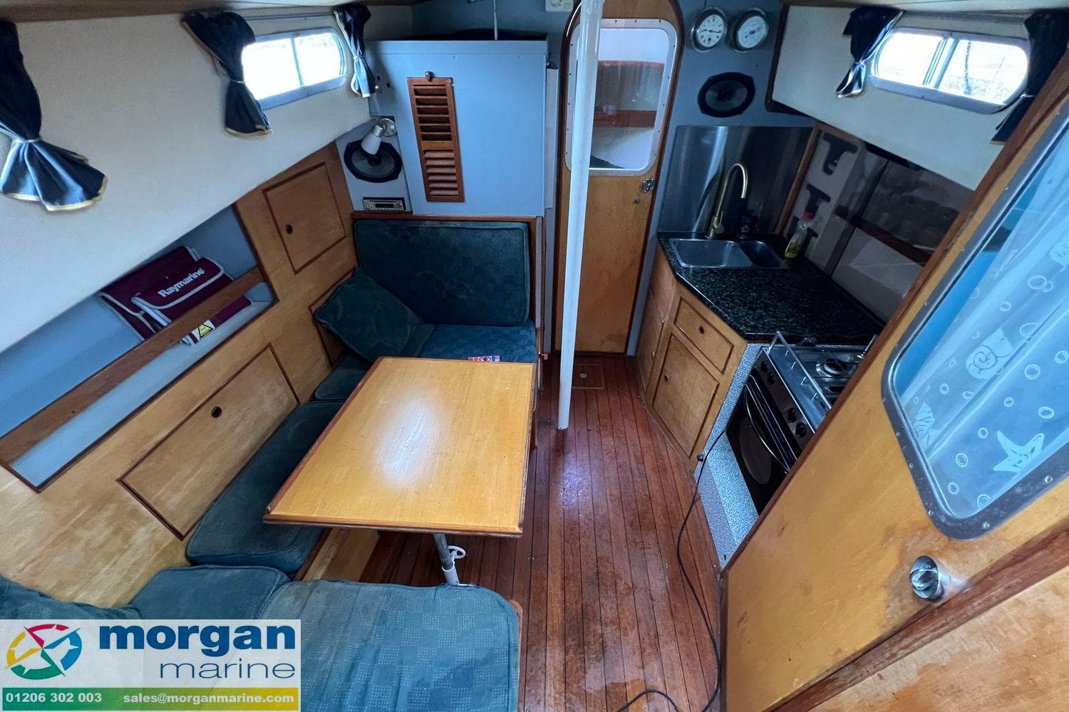 Interior of a 1972 Barbary Ketch sailboat with wooden furnishings and compact kitchen.