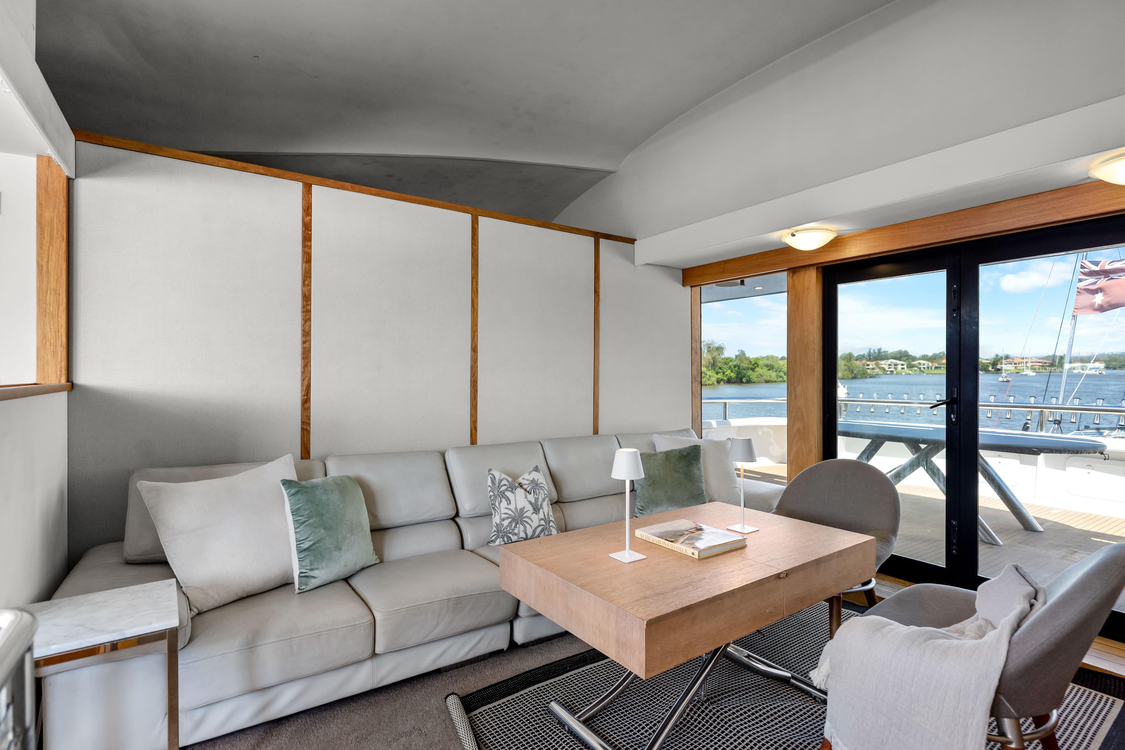 Luxurious yacht interior with modern furnishings, large windows, and scenic water views.