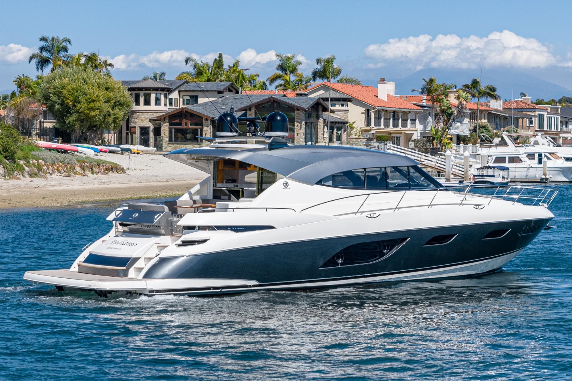 2020 Riviera 6000 Sport Yacht cruising near luxury waterfront homes.