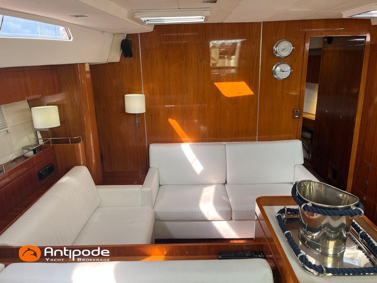 Luxurious Amel 64 yacht interior with white seating, wooden paneling, and nautical decor, 2010 model.