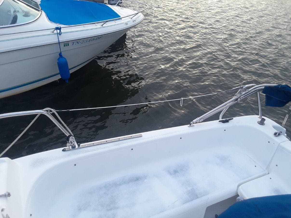 1996 MacGregor 26 "X" sailboat docked on calm water, adjacent to another boat.