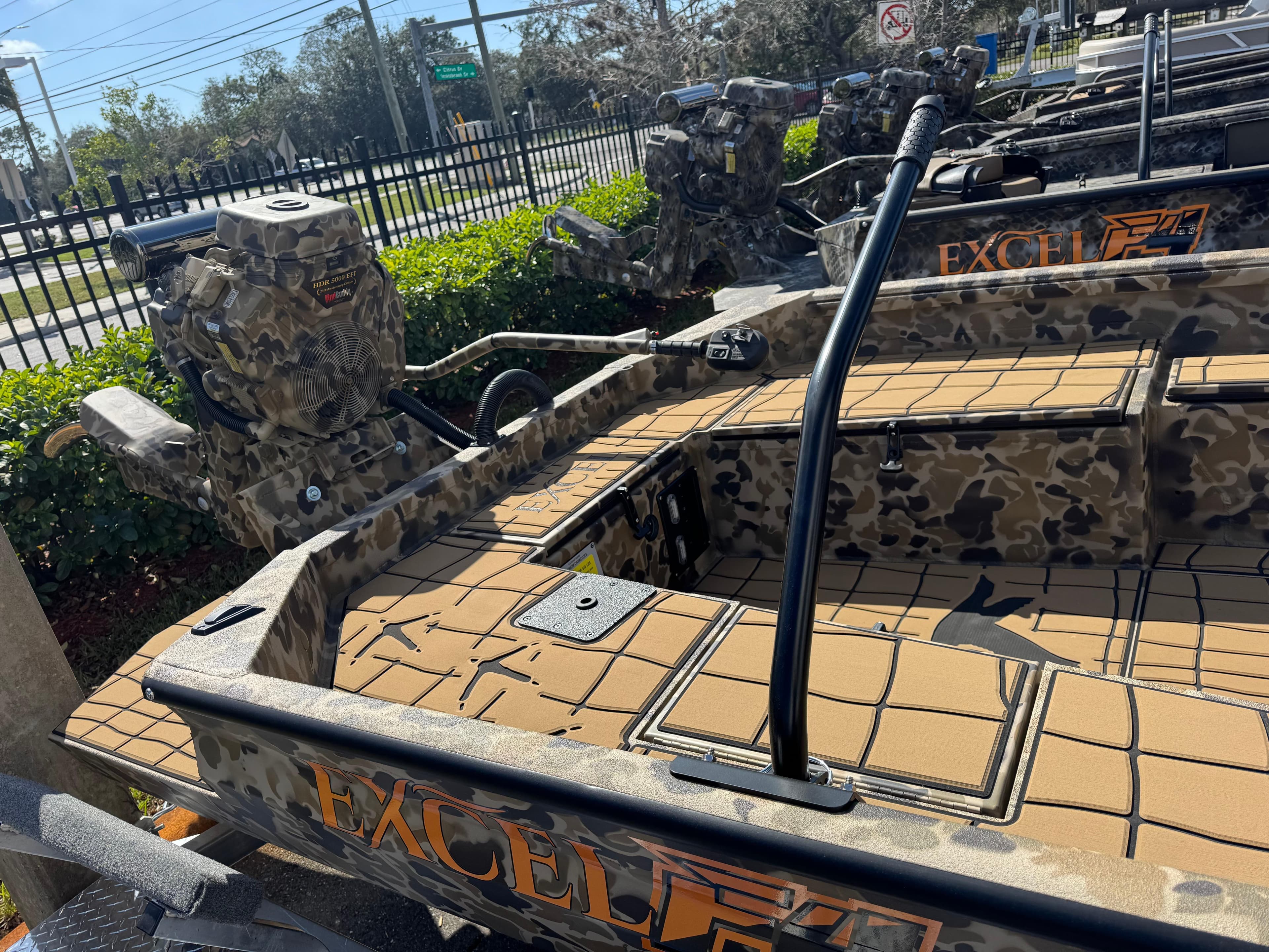 2025 Excel 1860 F4 Shallow Water boat with camouflage design, parked outdoors.