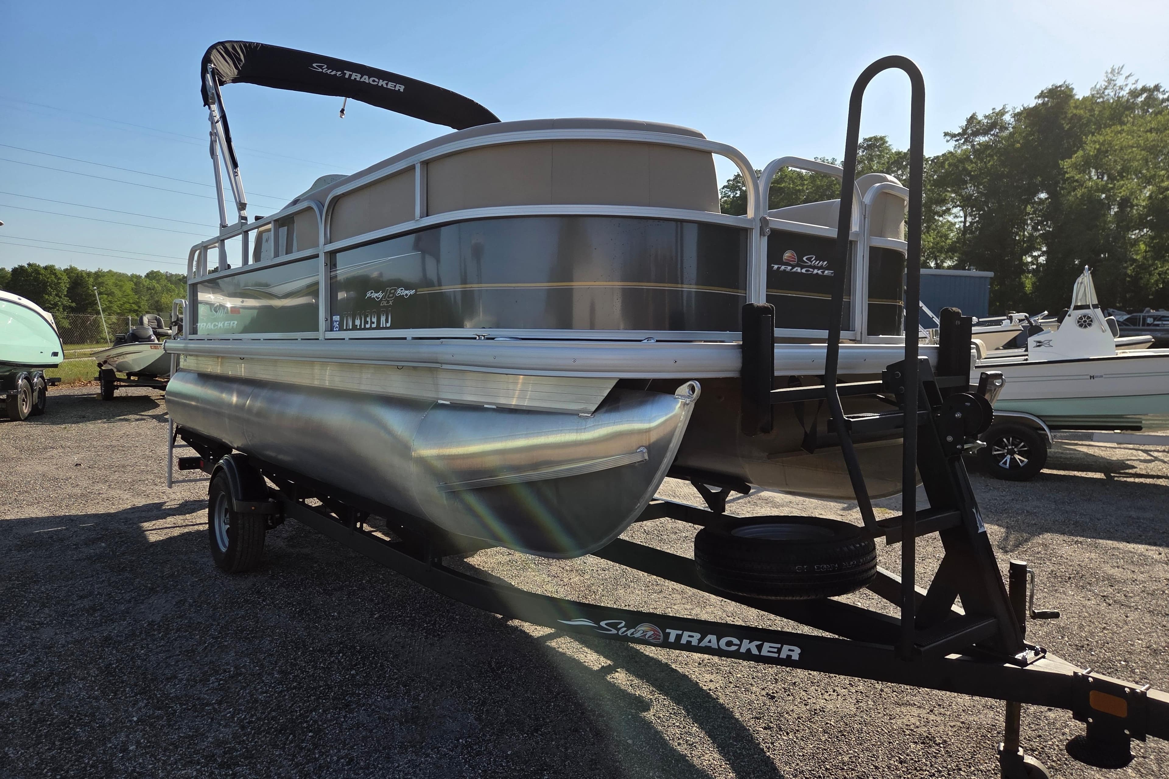 2022 Sun Tracker Party Barge 18 DLX pontoon boat on trailer in outdoor setting.