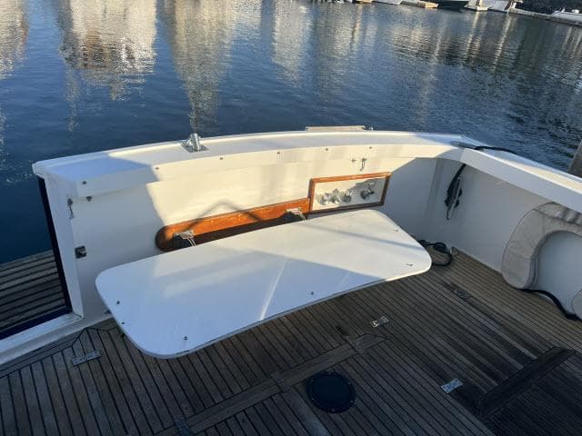 1999 Grand Banks Eastbay 38 boat deck with foldable table and wooden flooring.
