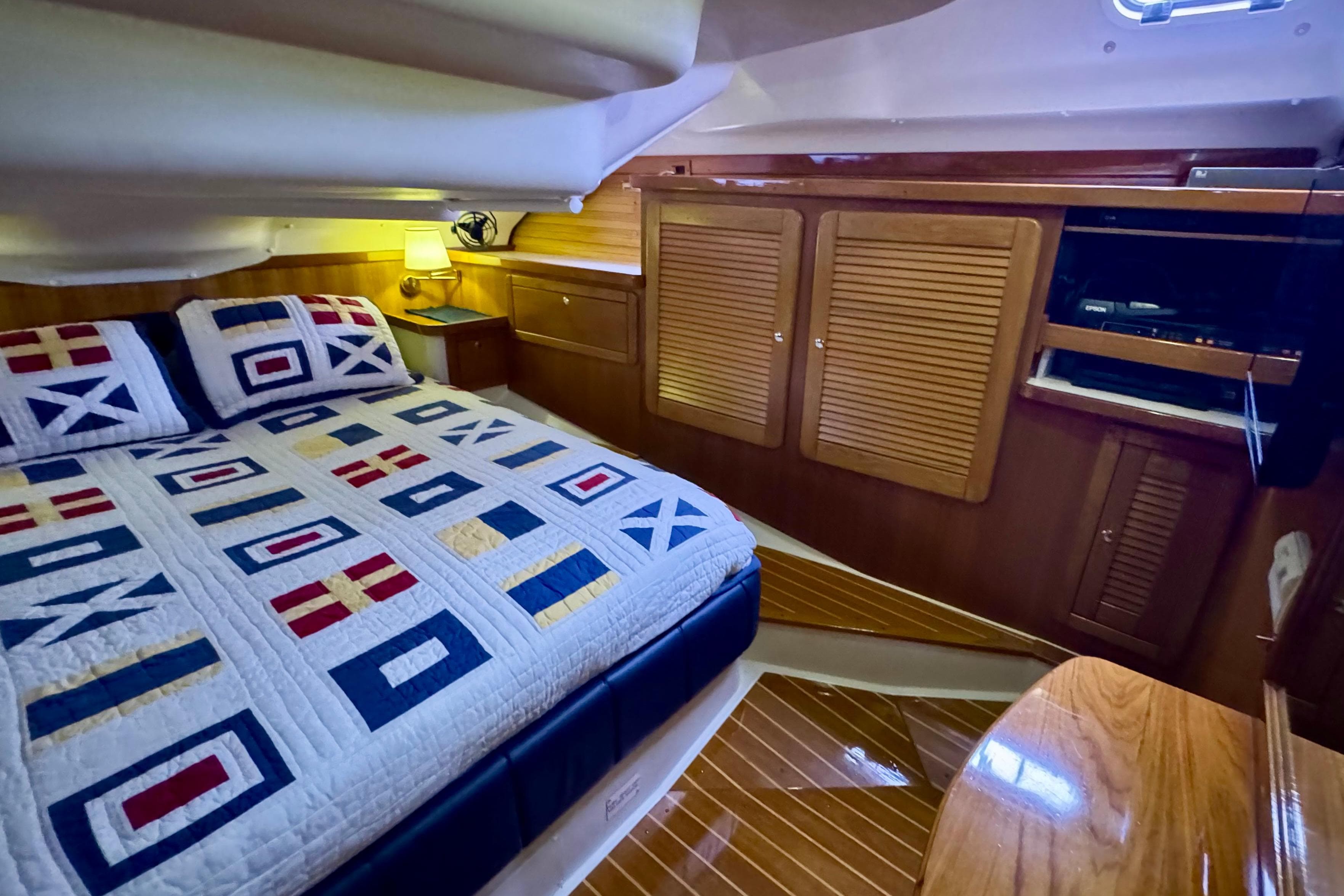 Luxurious cabin interior of 2005 Catalina 470 yacht with nautical-themed bedding.