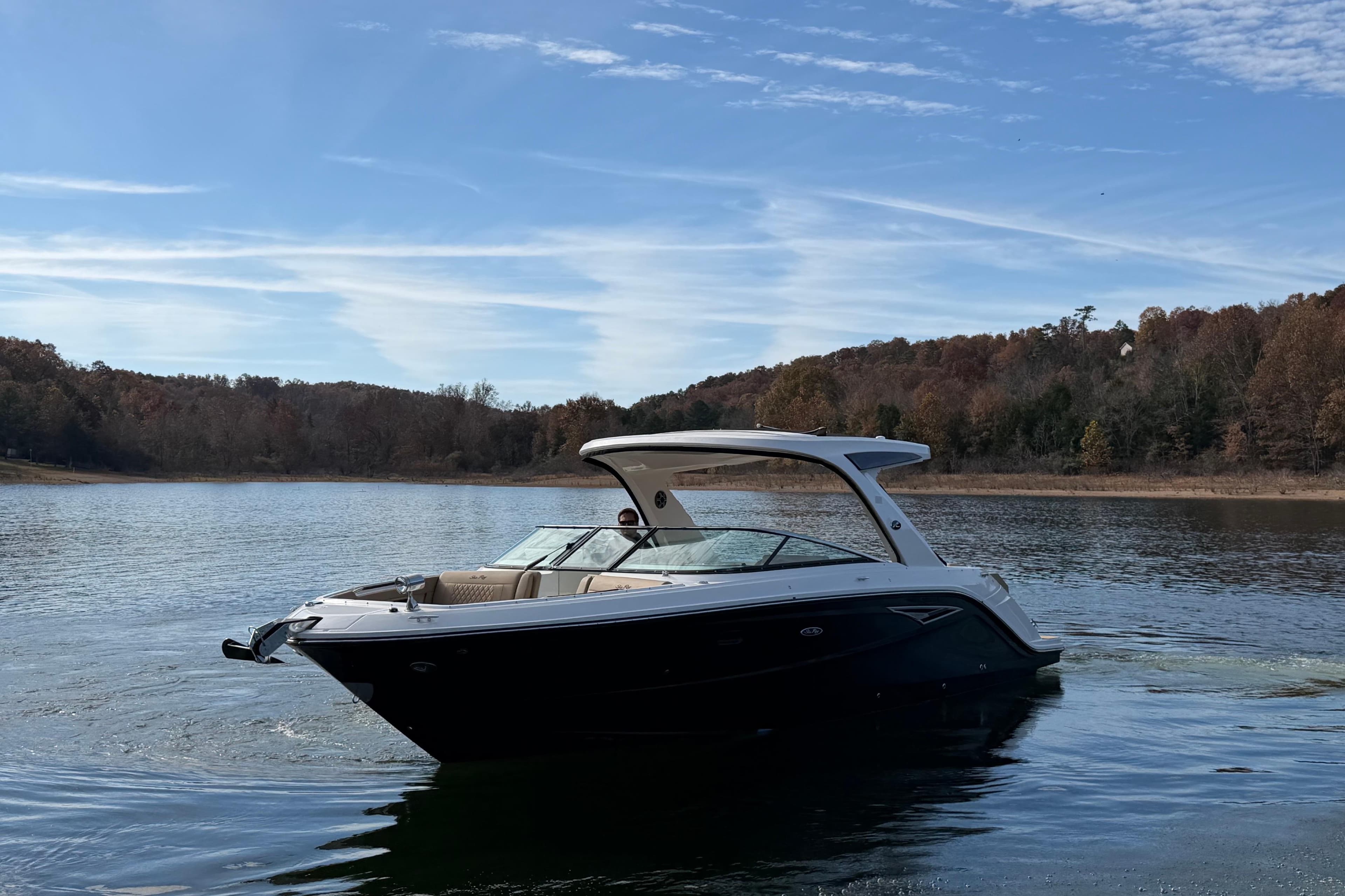 2026 Sea Ray SLX 310 boat on a serene lake with wooded shoreline.