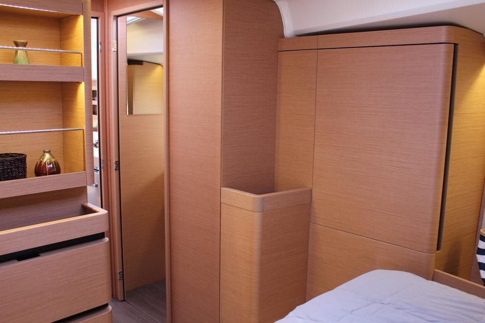 Interior of 2024 Jeanneau Sun Odyssey 490 yacht, featuring modern wood cabinetry and shelving.