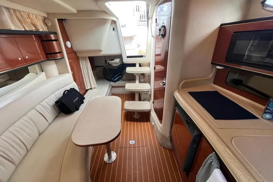 Interior of 2002 Sea Ray 300 Sundancer yacht with seating, table, and kitchenette.