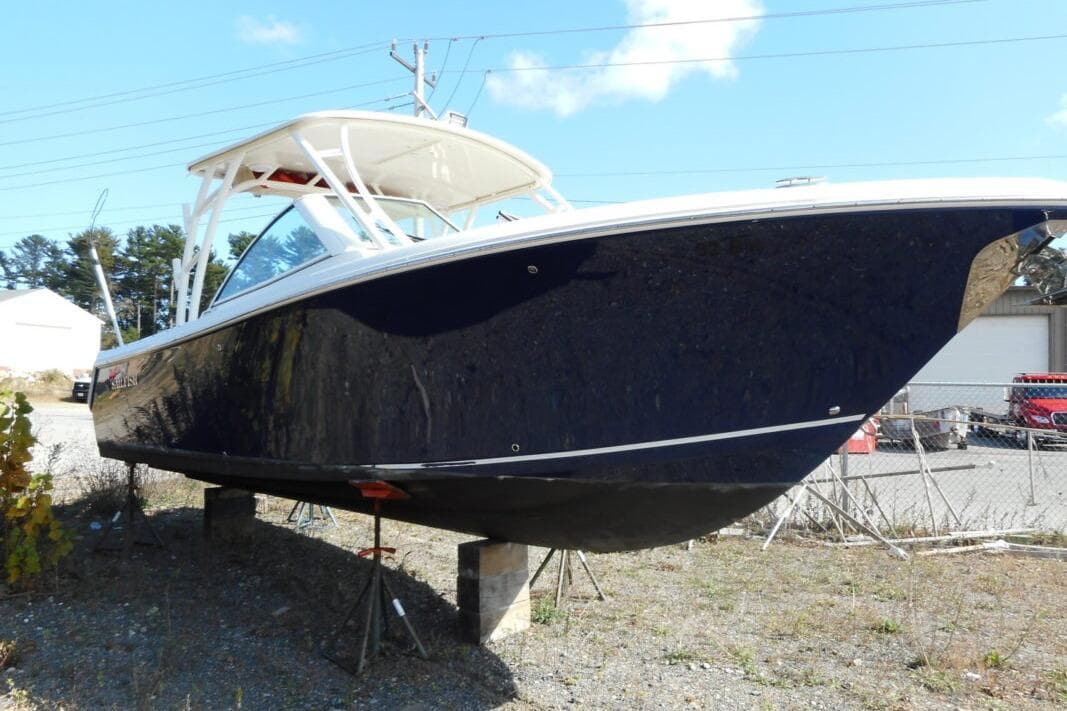 2020 Sailfish 275 DC boat on dry land, blue hull, white top, sunny day.