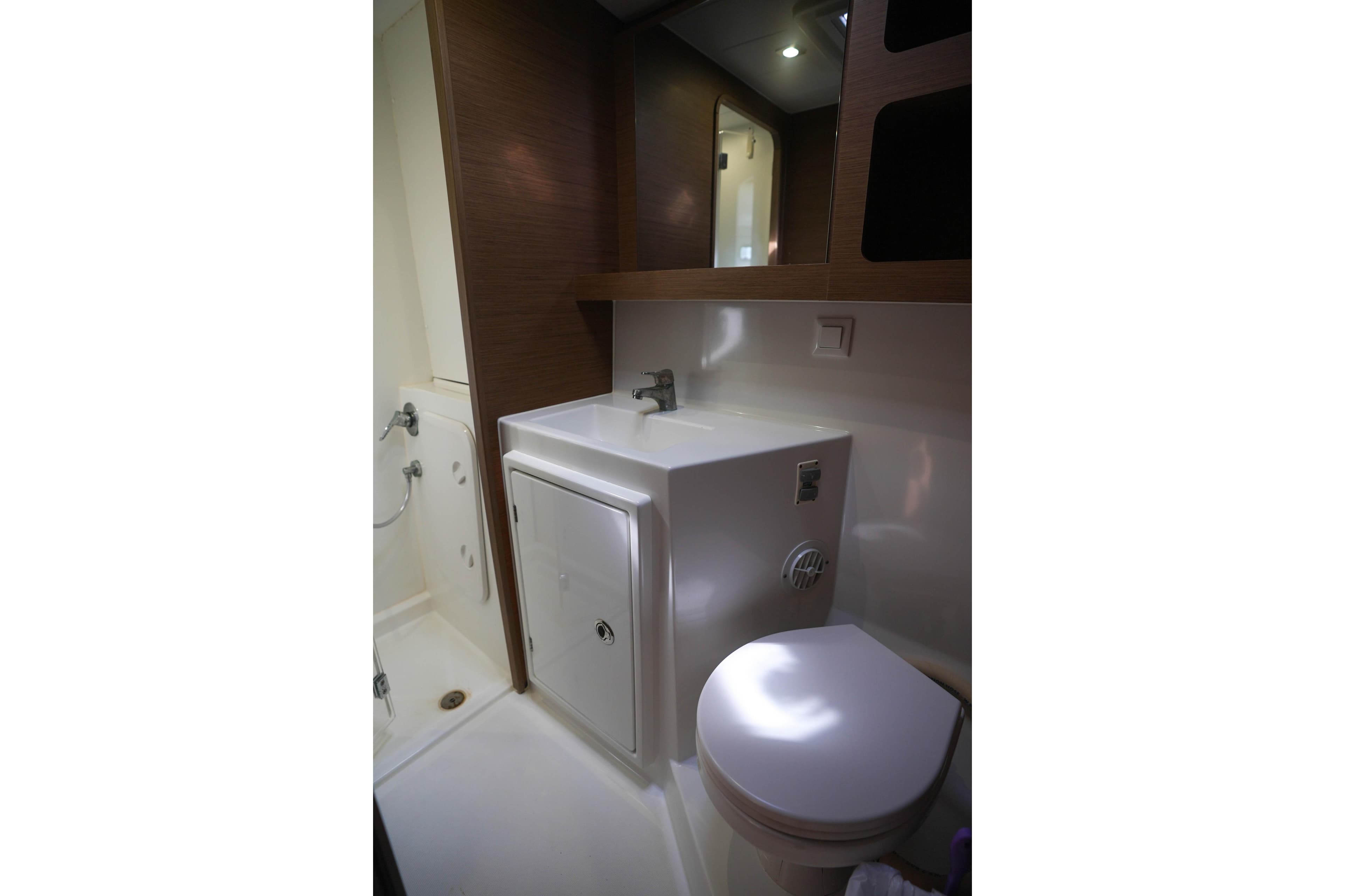 Bathroom interior of 2019 Lagoon 42 yacht, featuring sink, toilet, and shower area.