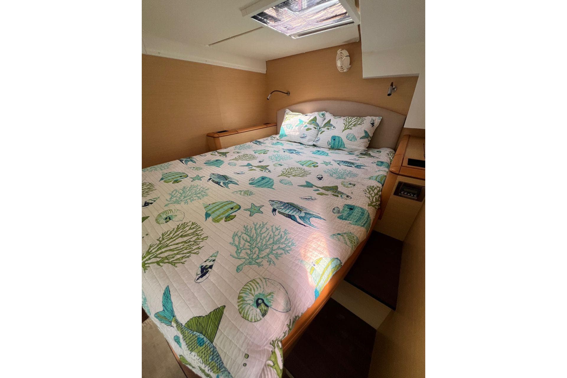 Cozy bedroom in 2012 Lagoon 500 yacht with ocean-themed bedding and natural light.