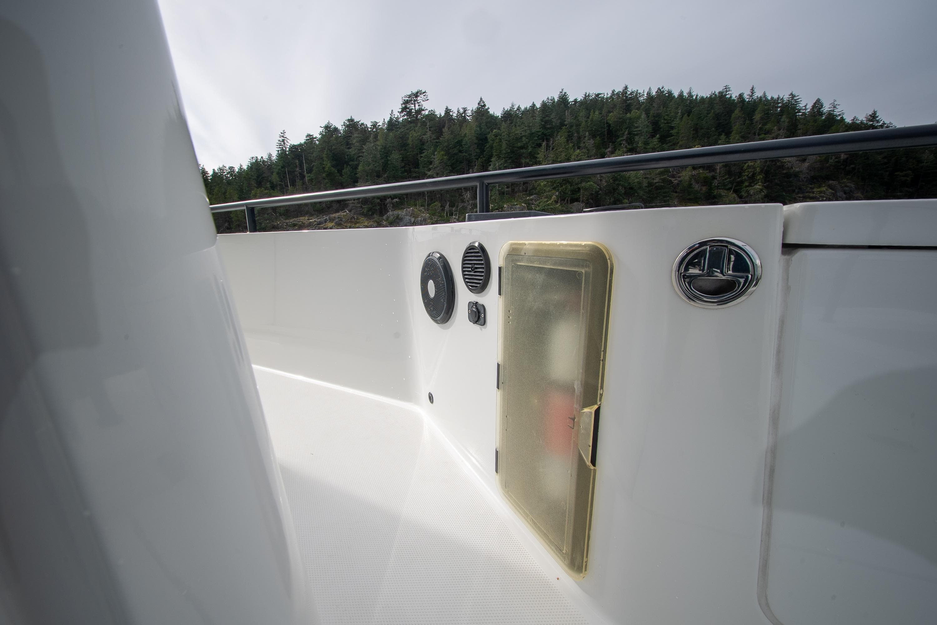 2021 Axopar 28 Cabin boat deck with storage compartment and scenic forest backdrop.