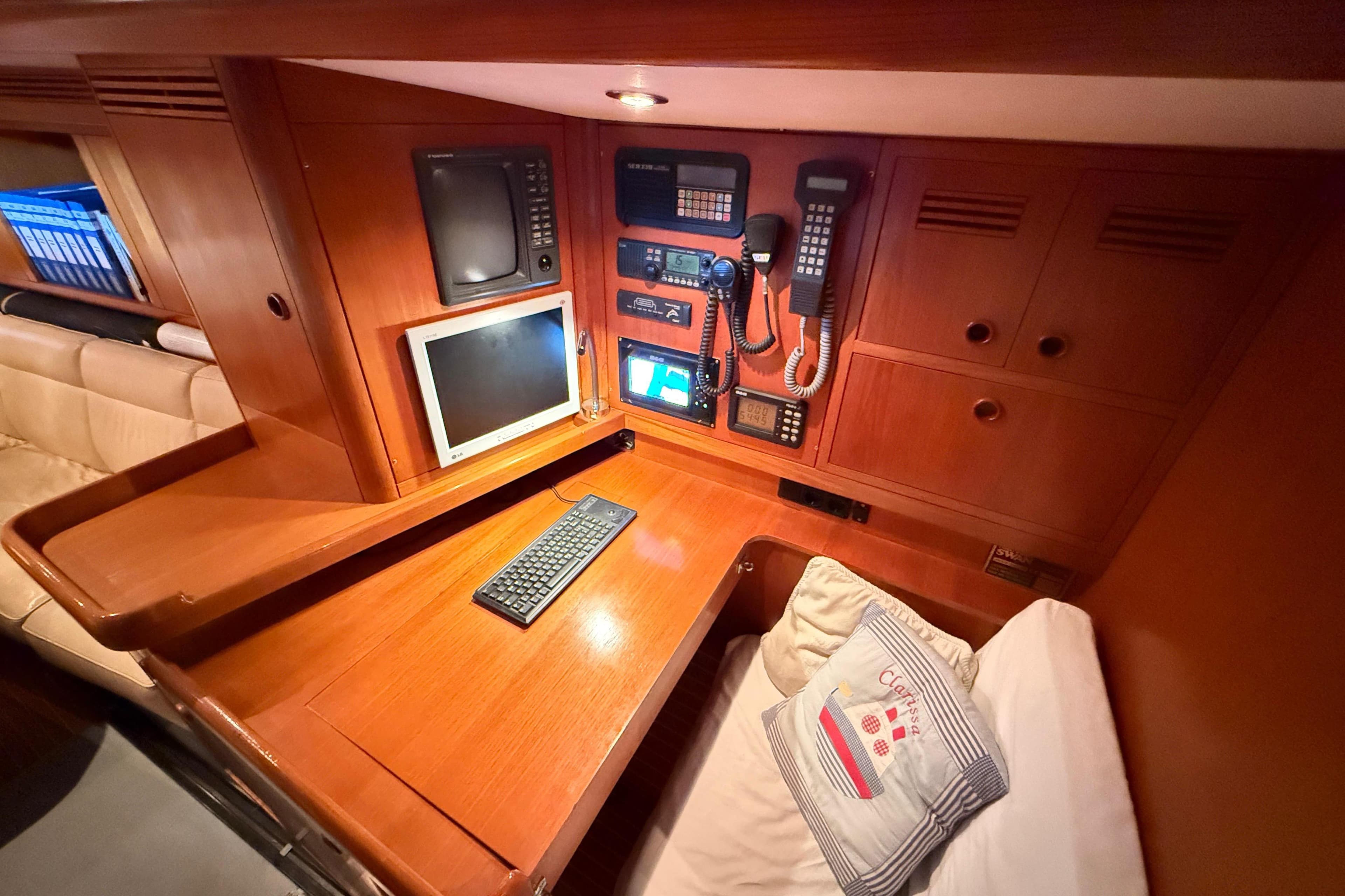 Navigation station inside 1997 Nautor Swan 56R yacht with control panels and desk.