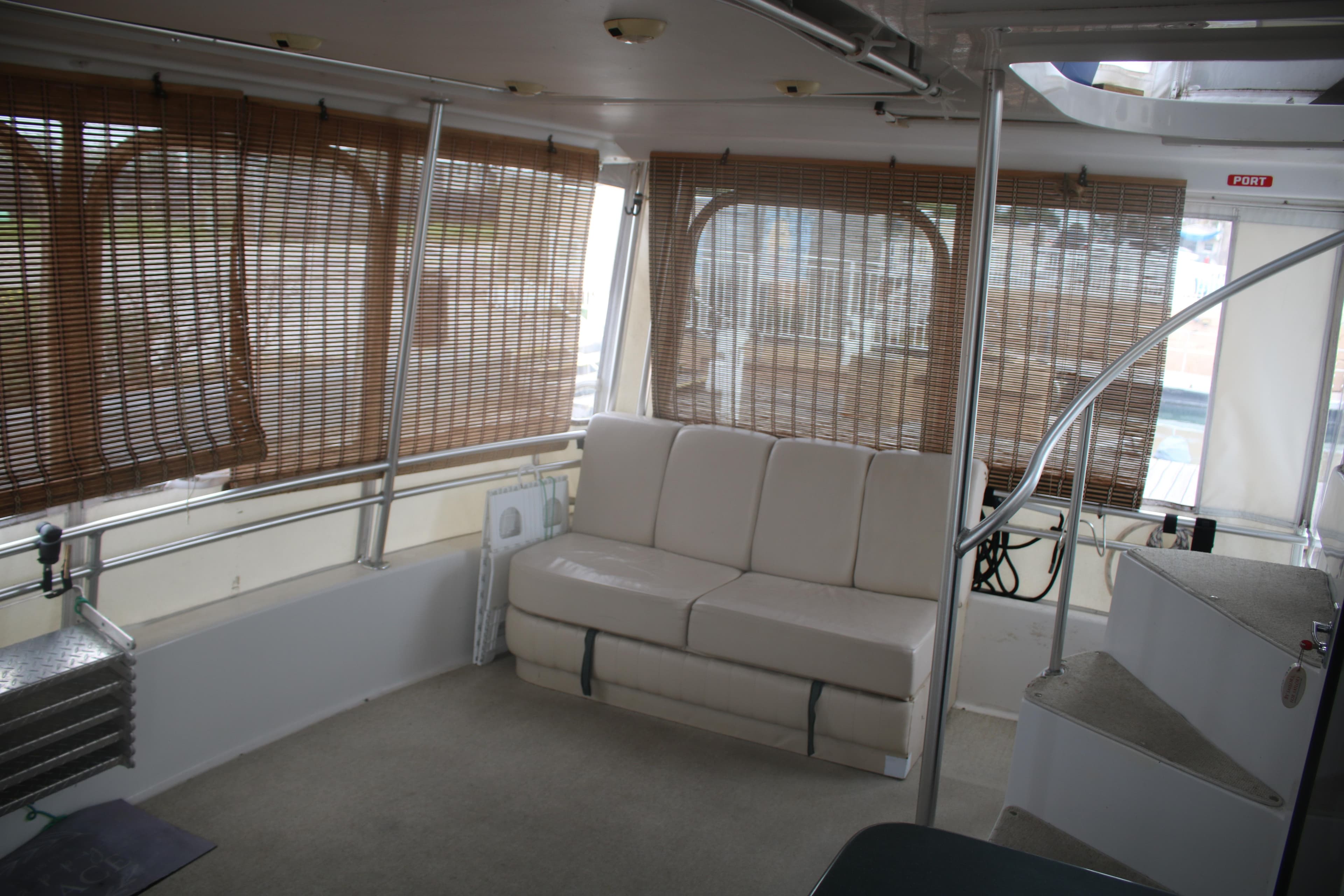 Interior of 1998 Mainship 47 Motor Yacht with beige seating and bamboo blinds.