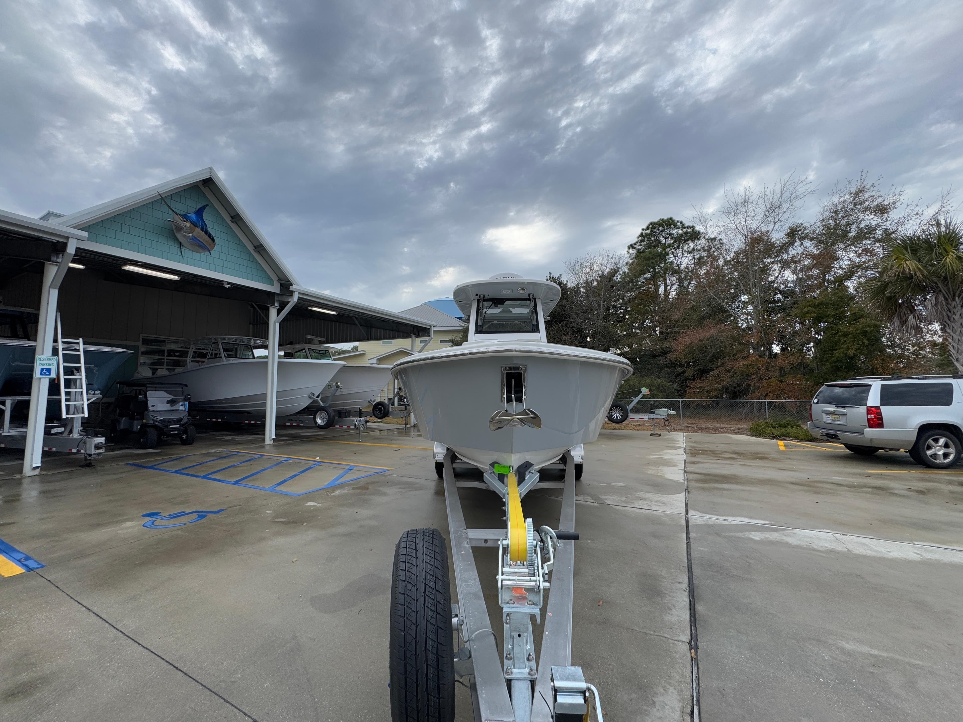 2025 Solace 28 HCS boat on trailer at dealership, cloudy sky background.