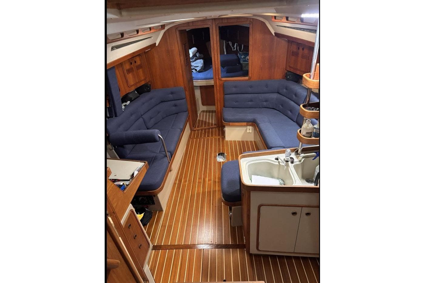 Interior of a 1990 C&C 37/40 Plus sailboat with blue seating and wooden flooring.