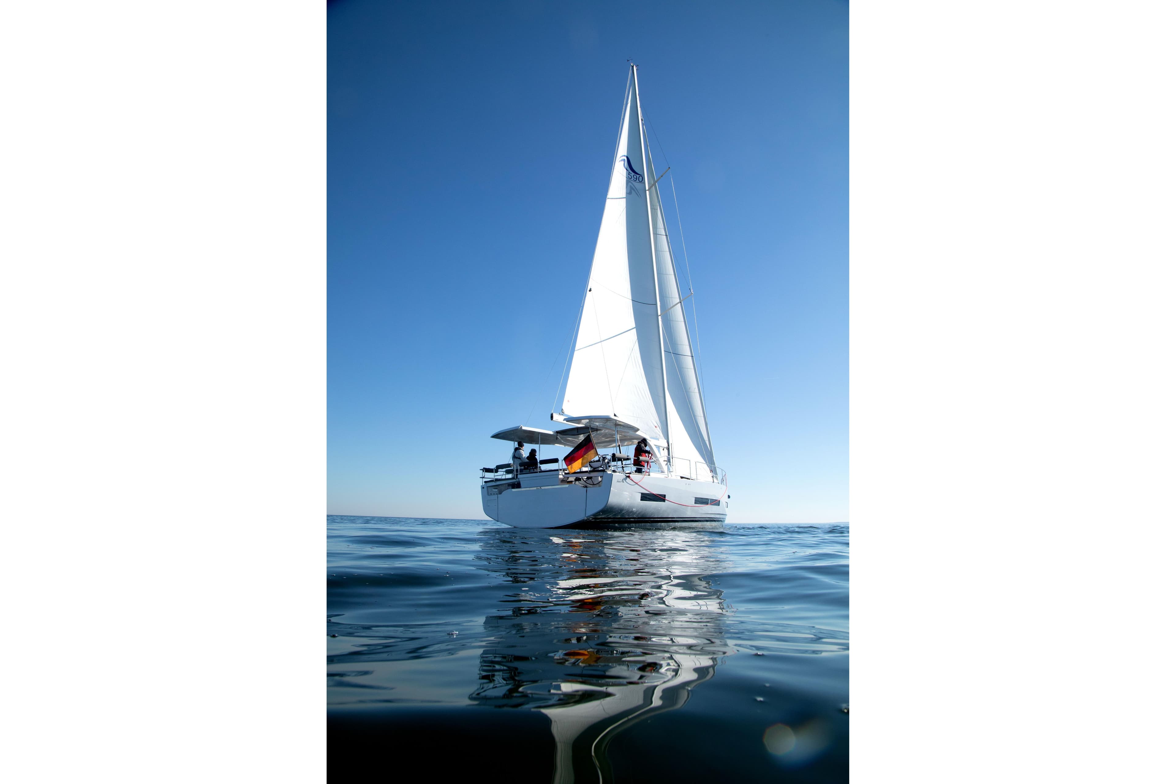 Sailing yacht Hanse 590, 2026 model, gliding on calm ocean waters under clear blue skies.