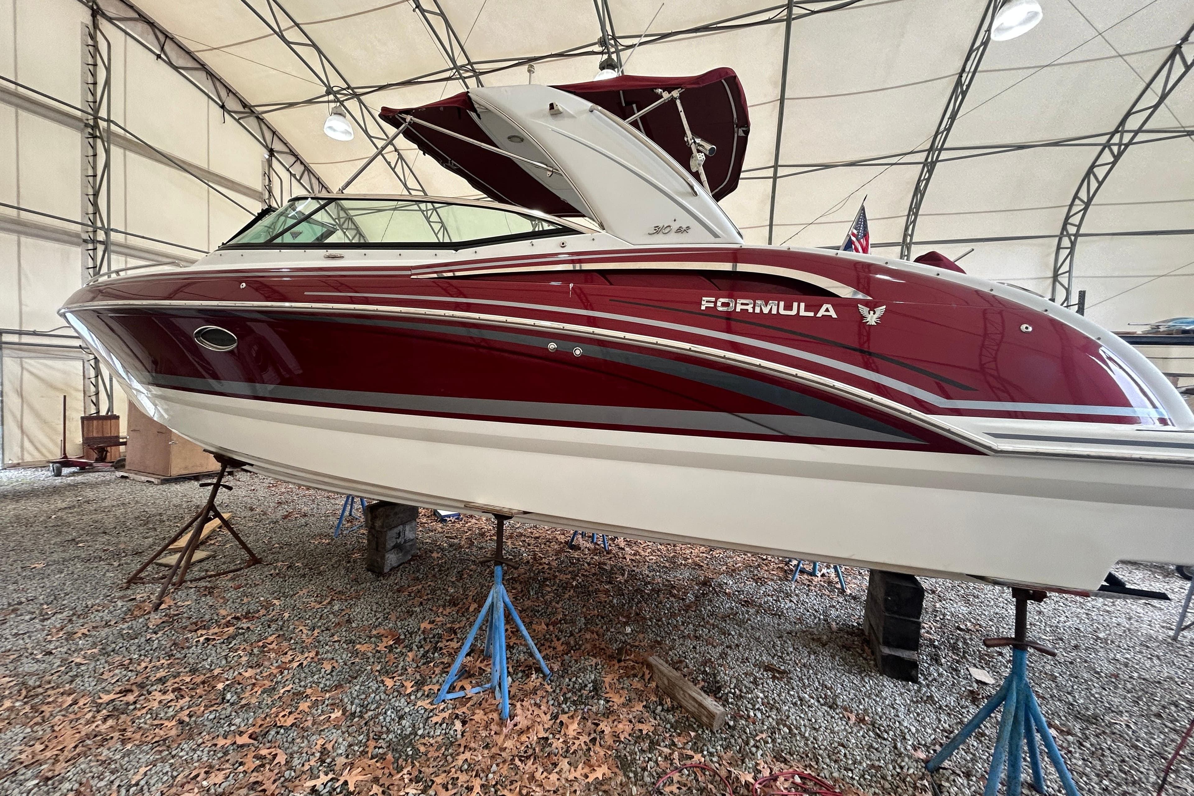 2015 Formula 310 Bowrider in storage, red and white design, elevated on stands.