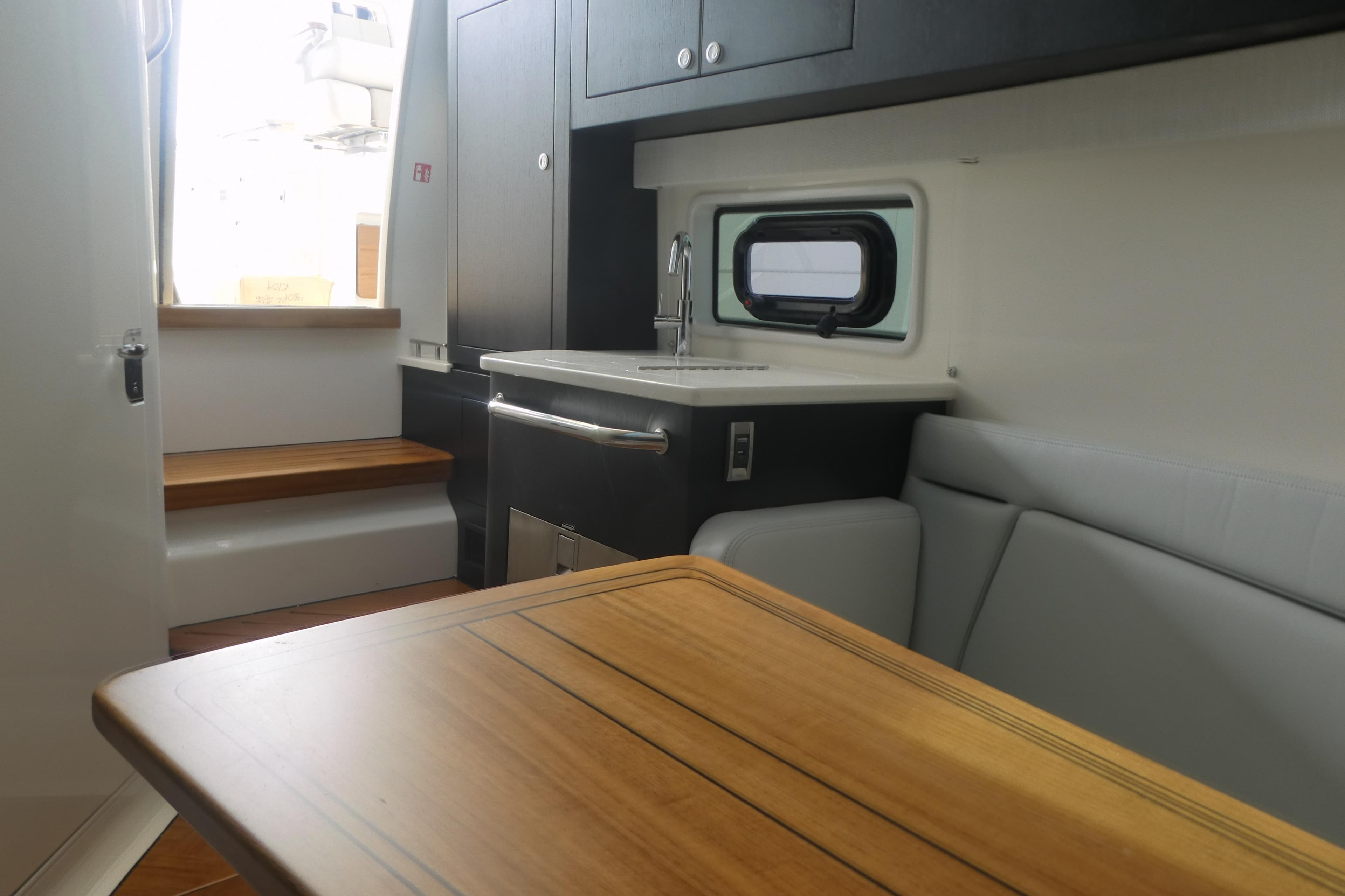 Interior of 2026 Boston Whaler 380 Realm, featuring a compact kitchen and seating area.