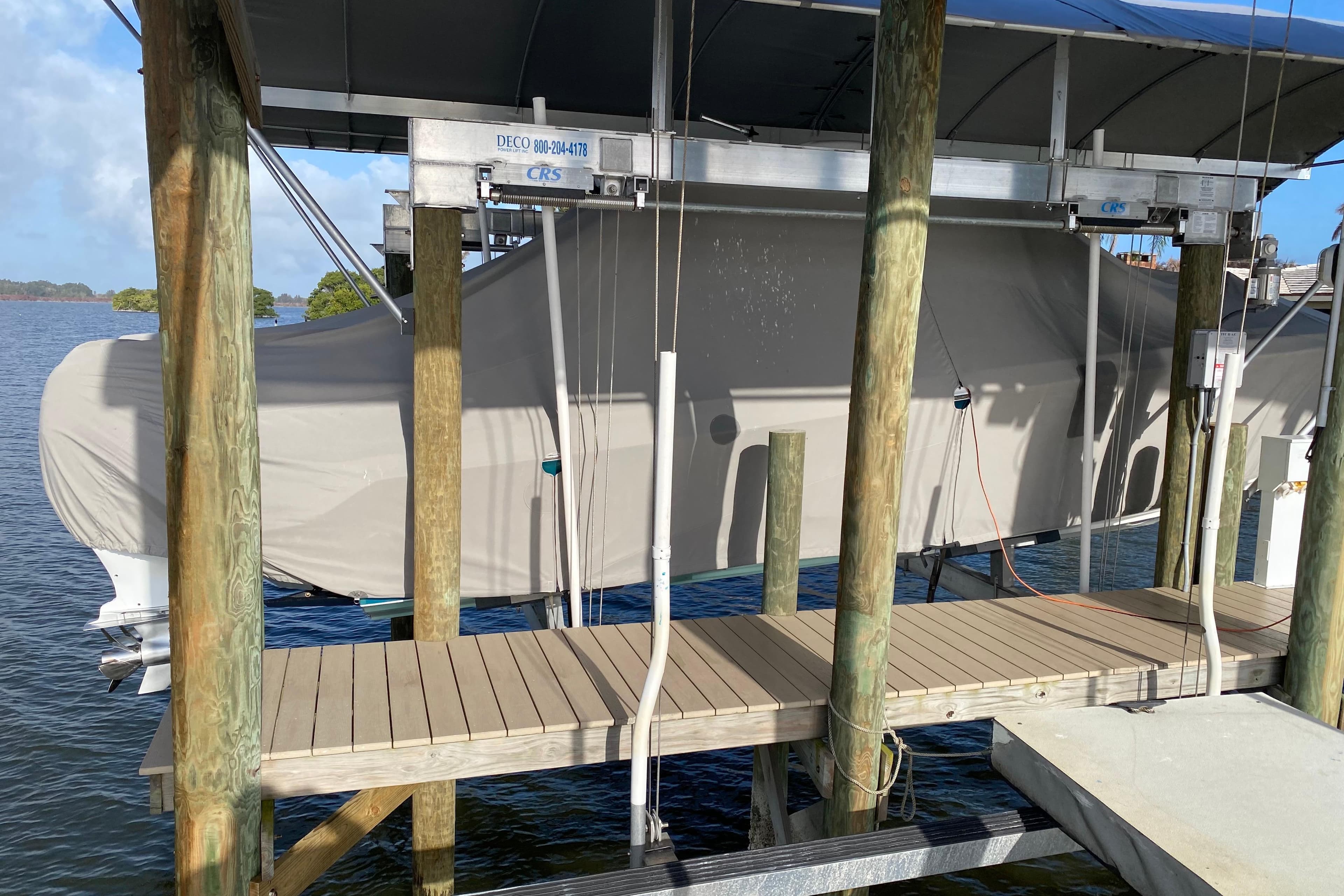 Covered 2018 Nor-Tech 340 Sport Center Console on a boat lift by the water.