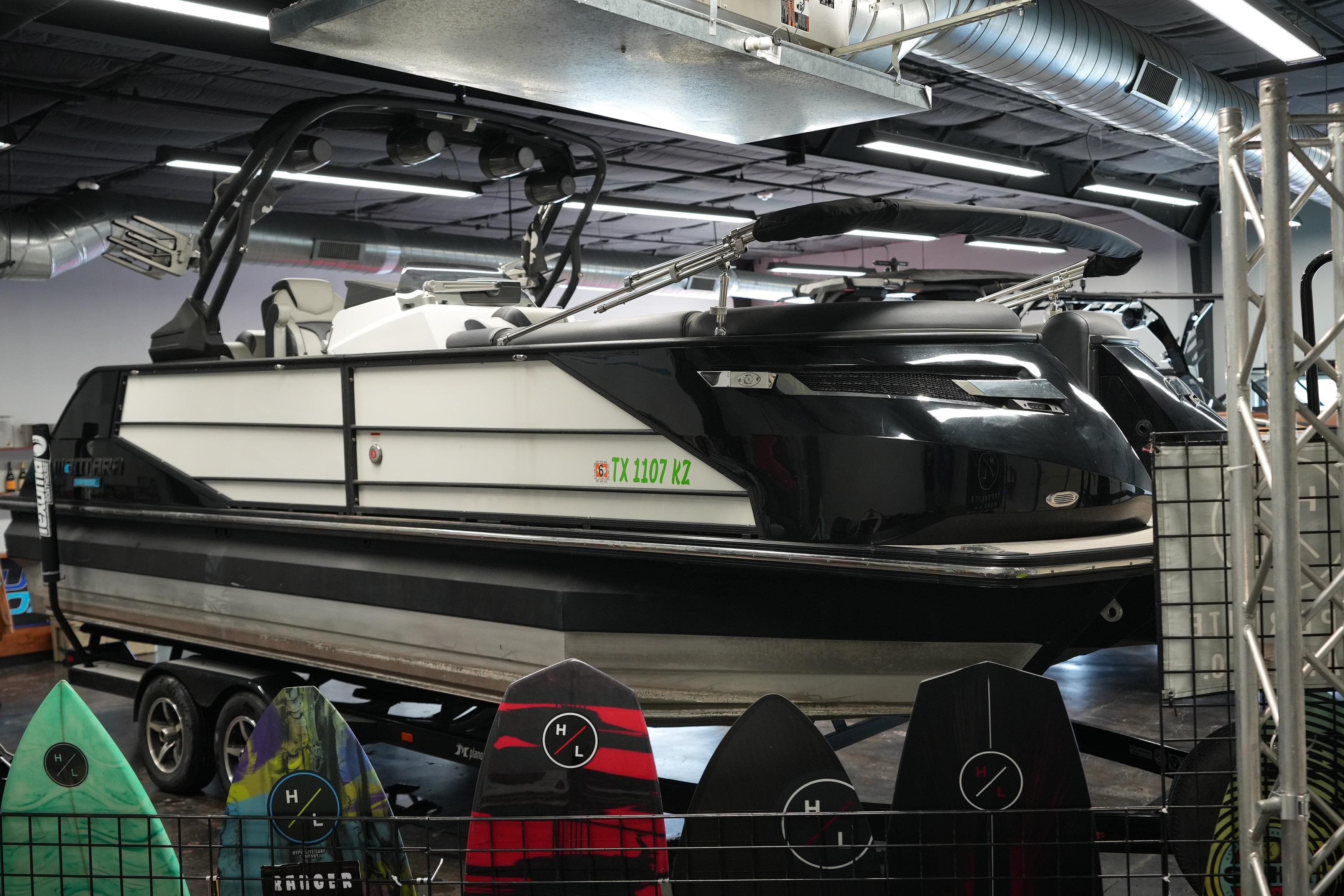 2024 Montara SURF BOSS 25 boat displayed indoors with surfboards in the foreground.