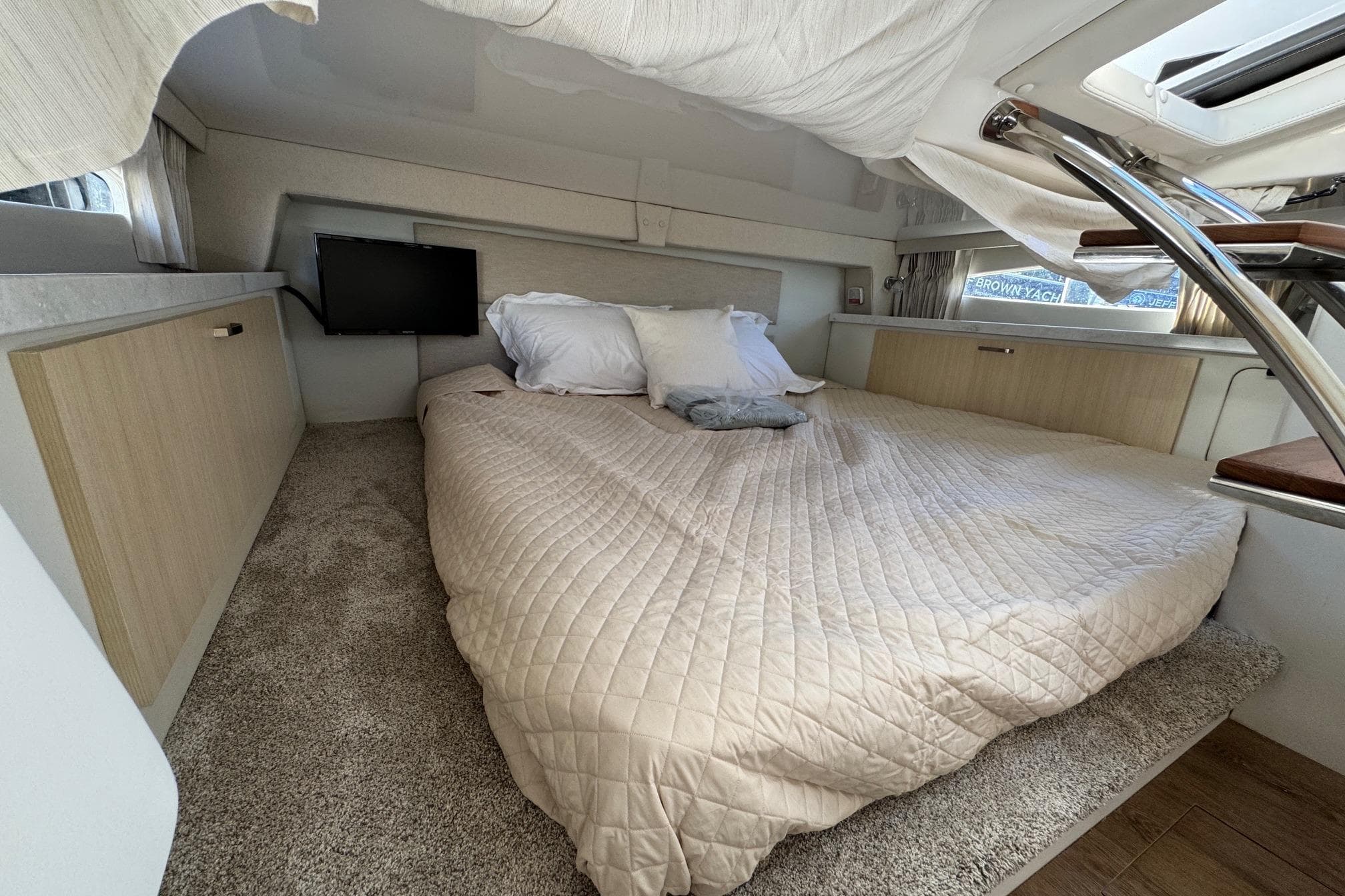 Cozy cabin interior of 2026 Regal 33 XO yacht with bed and TV.