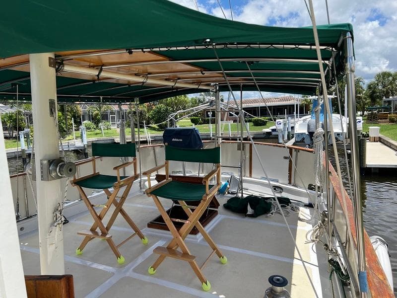 1981 Island Trader 46 sailboat deck with green canopy and chairs, docked at marina.