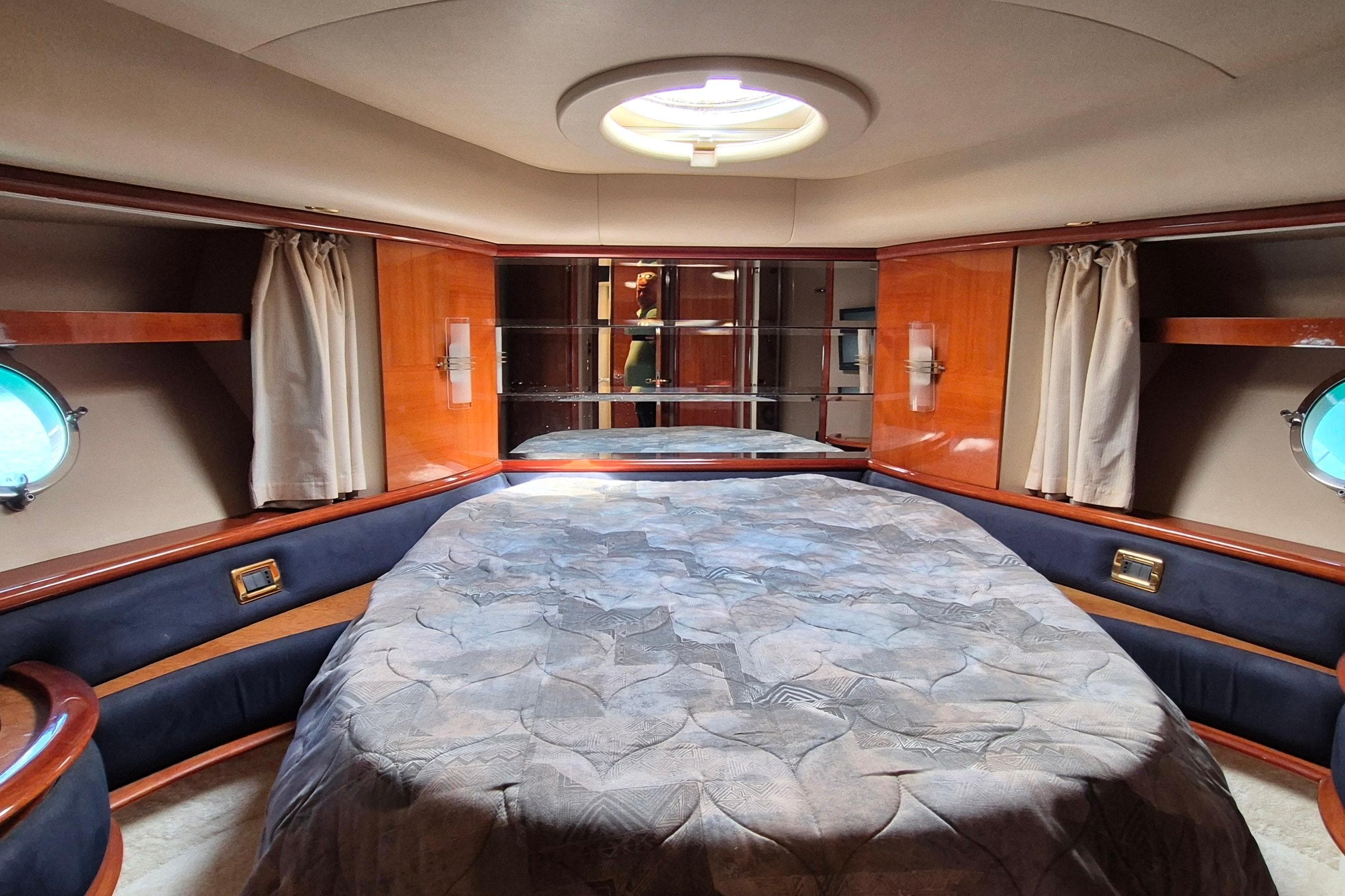 Luxurious bedroom interior of a 2003 Azimut 62 yacht with elegant wood finishes.