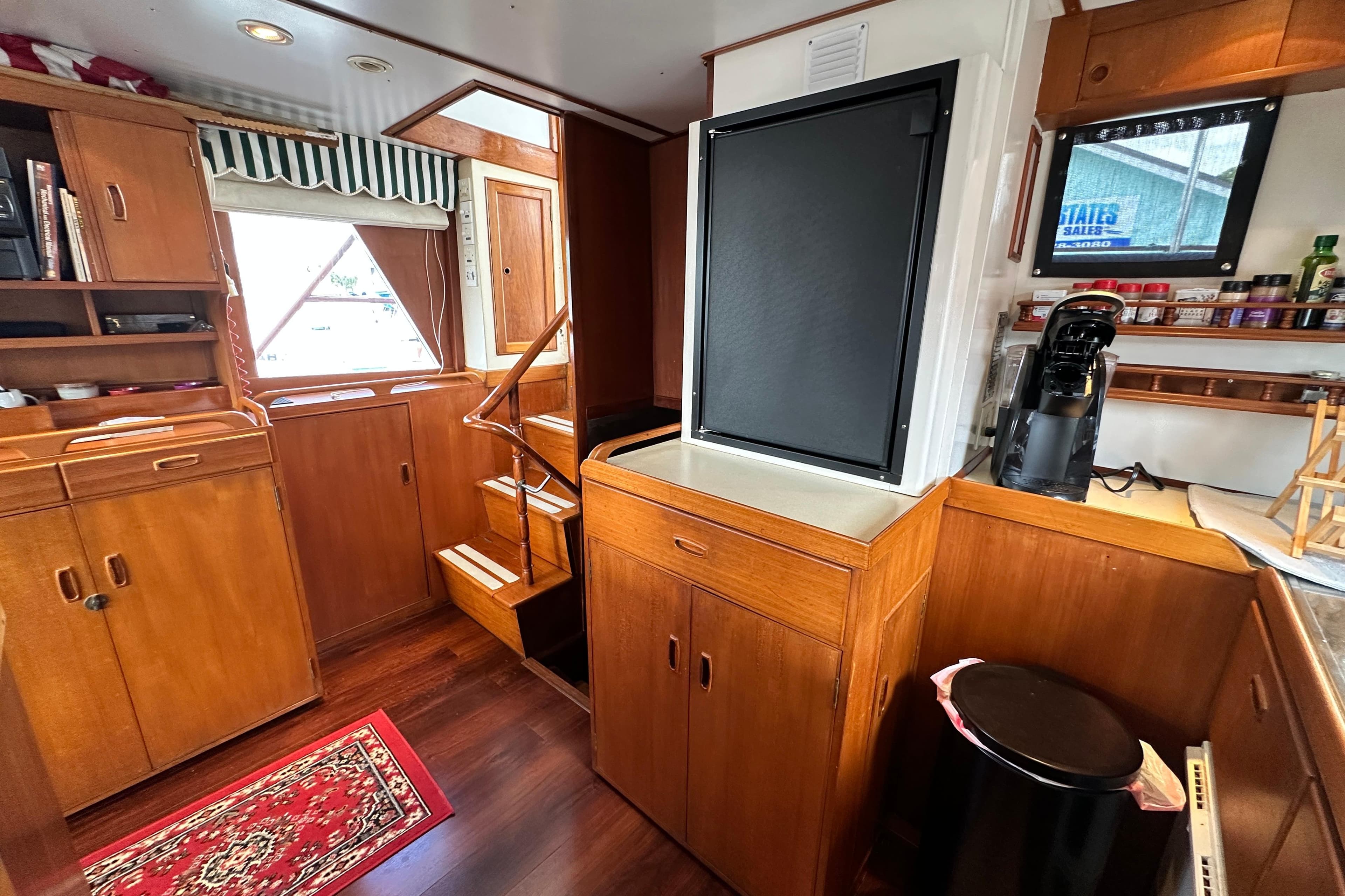 1980 Island Gypsy yacht interior with wooden cabinetry, stairs, and kitchen area.