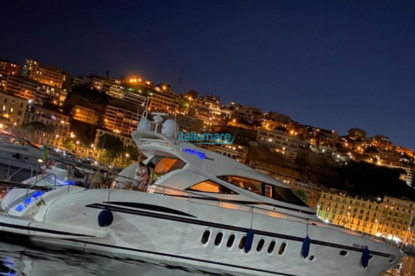 2025 Alalunga Open 85 Sport X yacht docked at night with city lights in background.