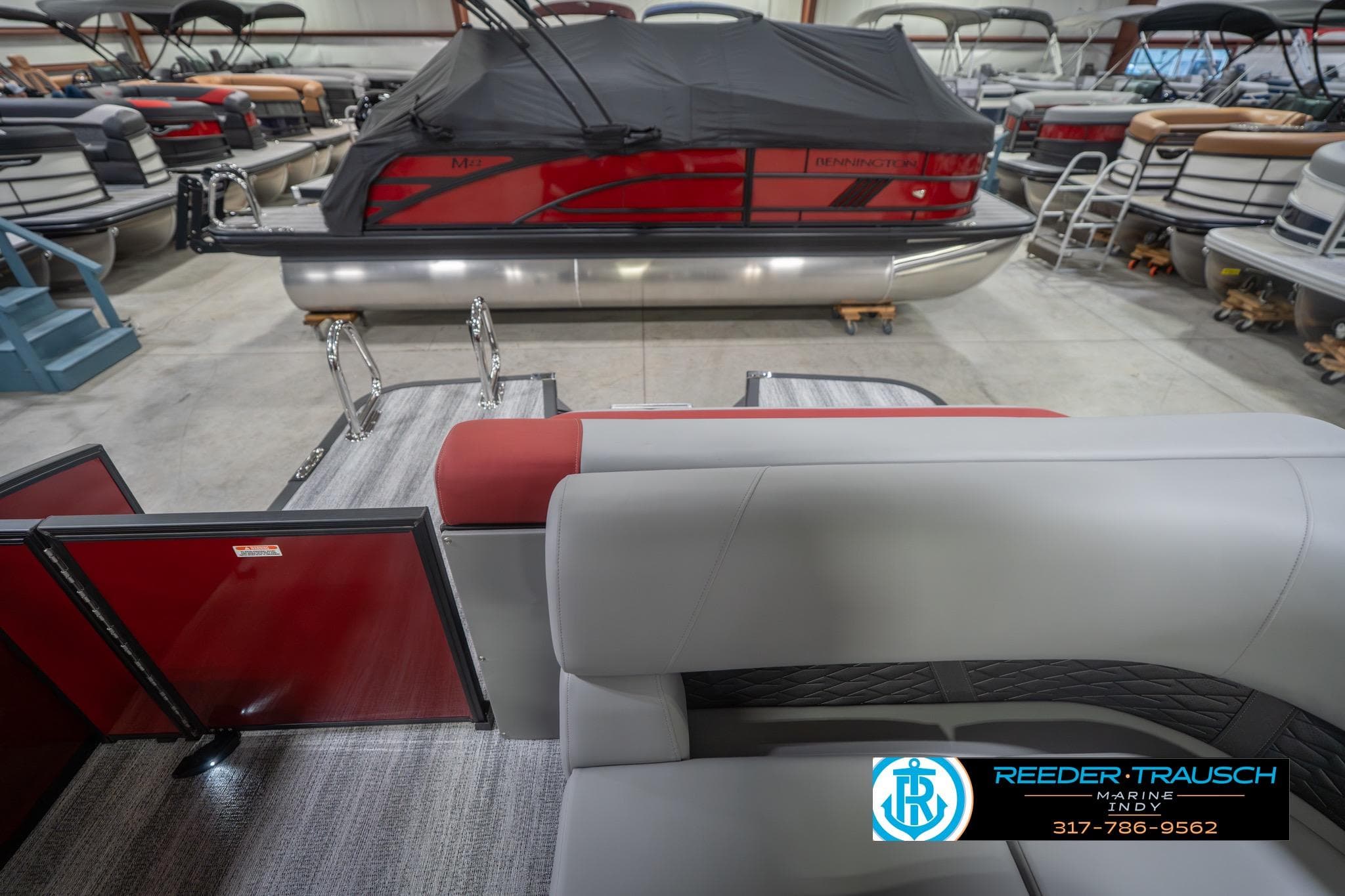 2026 Bennington 22 SLJ pontoon boat interior with red and gray seating in showroom.
