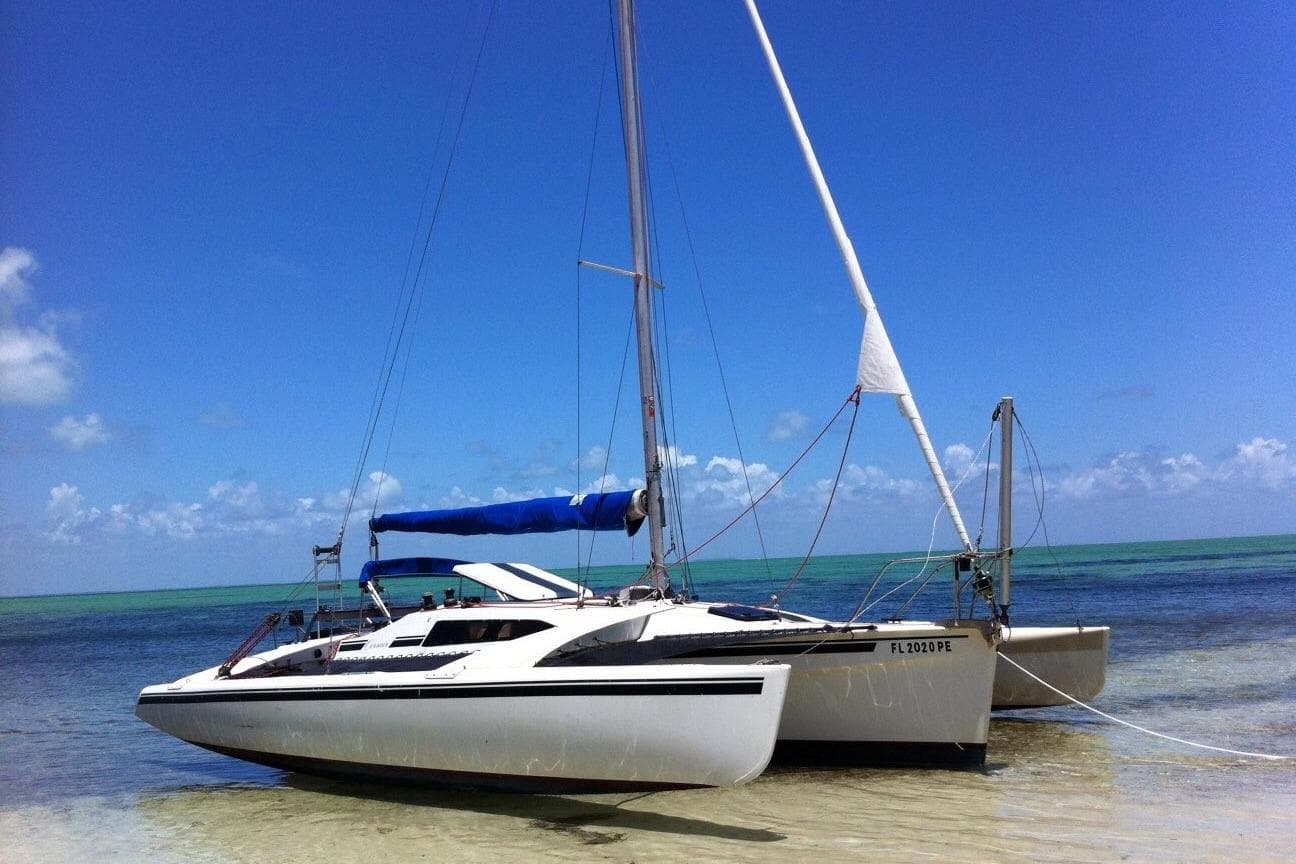 Corsair F27 trimaran sailboat from 1989 on a sunny beach with clear blue skies.