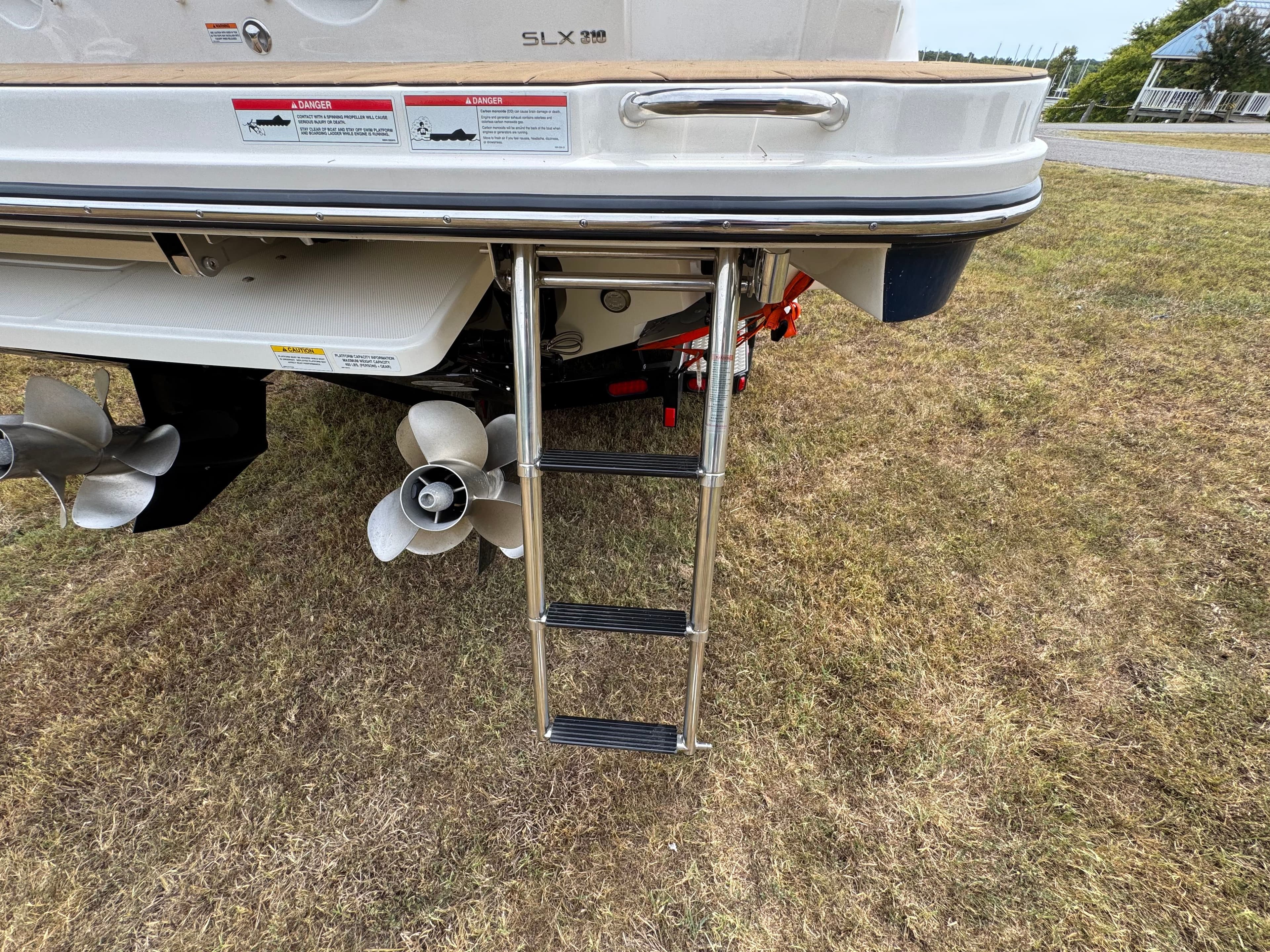 2022 Sea Ray SLX 310 boat with ladder and propellers on grassy area.