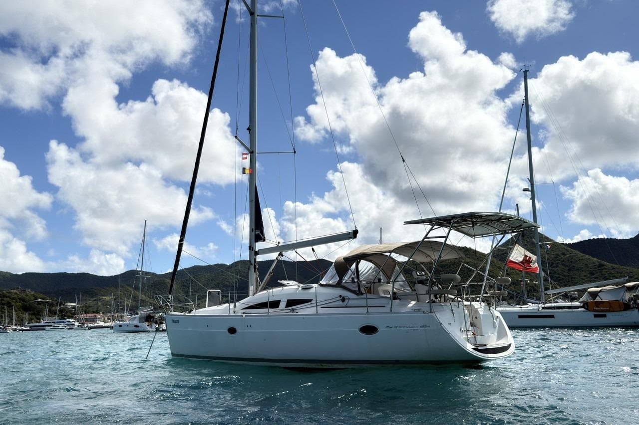 Sailboat Elan Impression 384, 2006 model, anchored in a scenic bay with mountains.