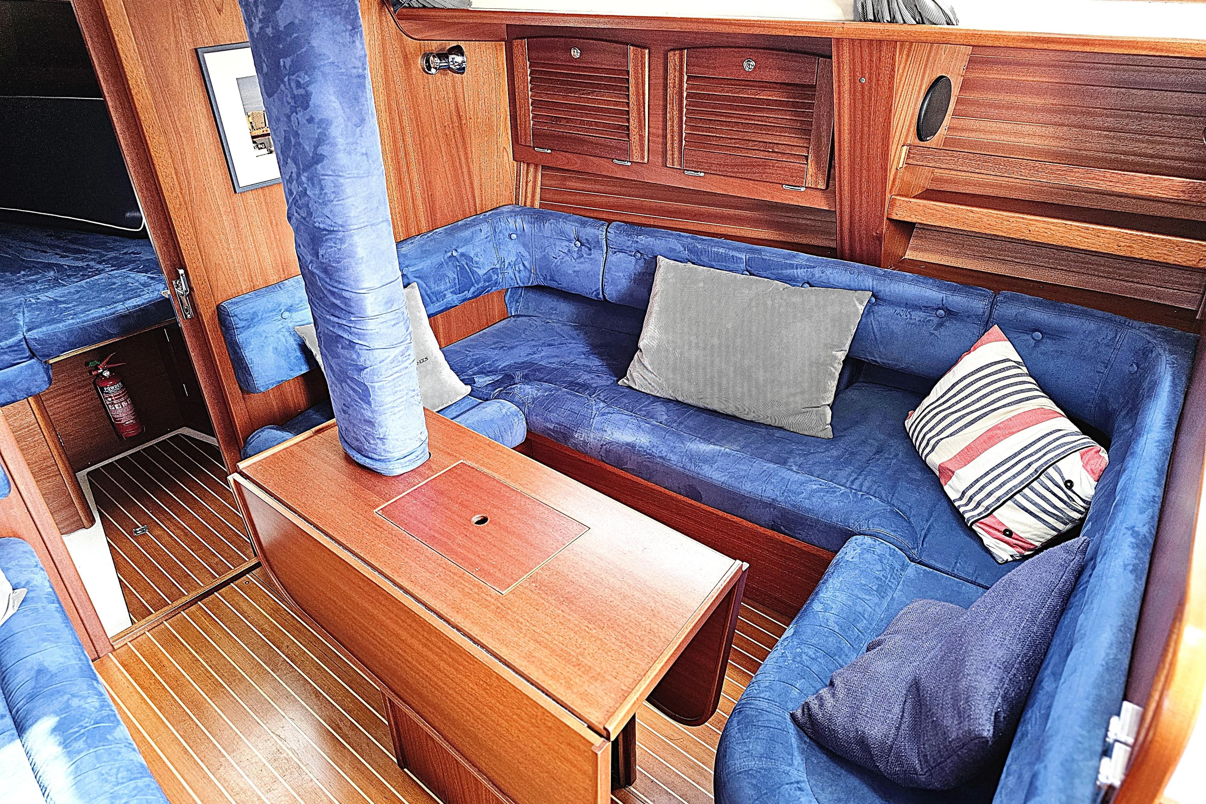 Cozy interior of a 2006 Maxi 1100 sailboat with blue seating and wooden accents.