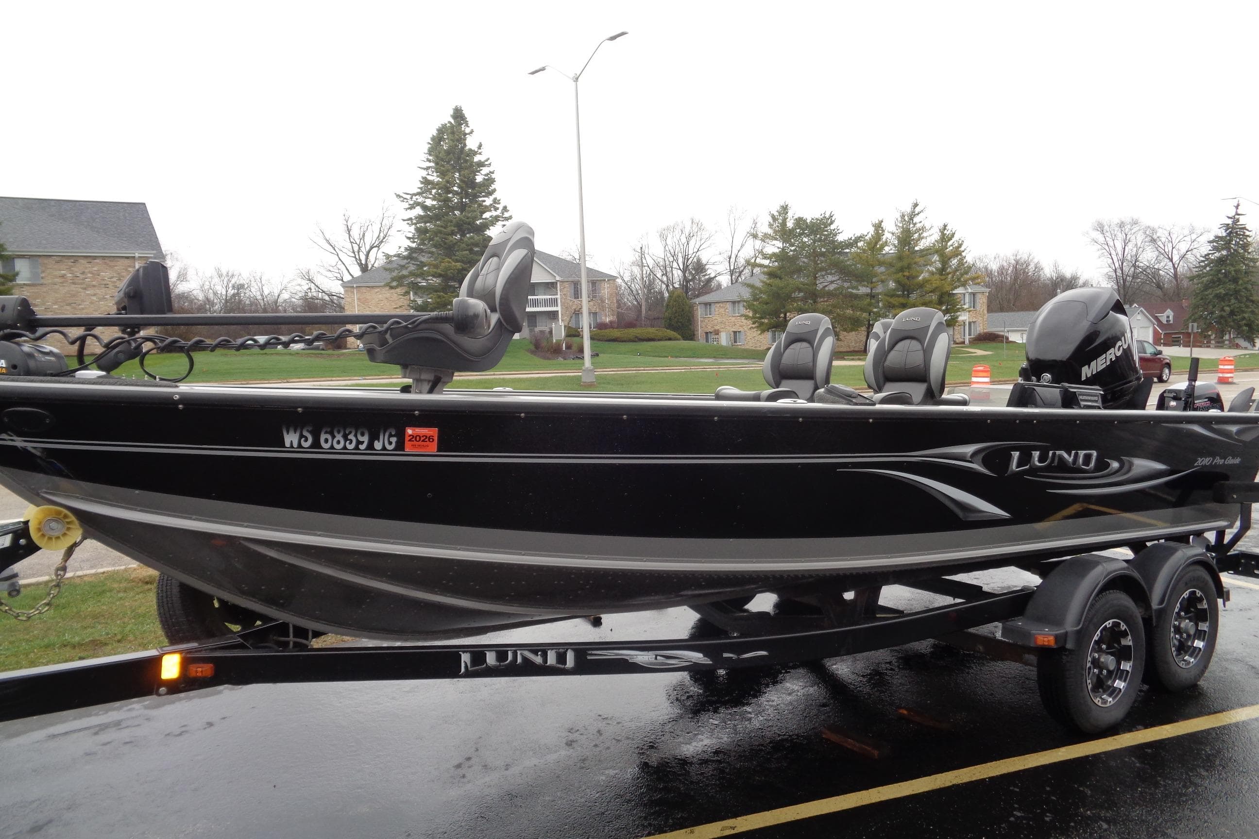 Lund 2010 Pro Guide boat on trailer, parked outdoors, overcast day.