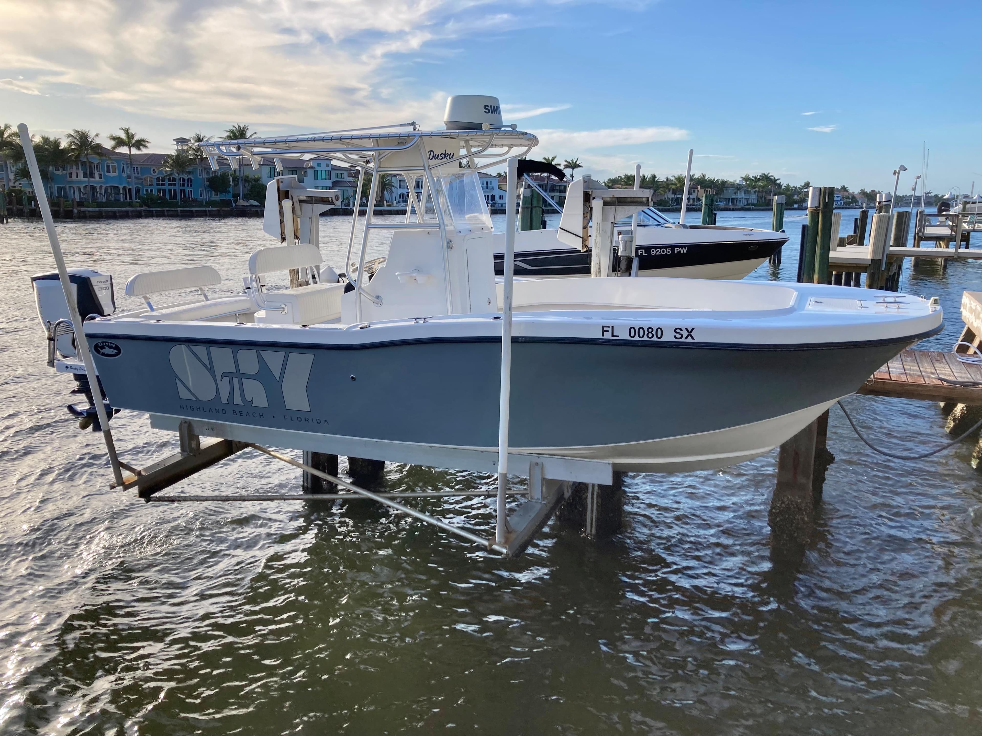 2021 Dusky 252 T boat docked on a lift by the waterfront.