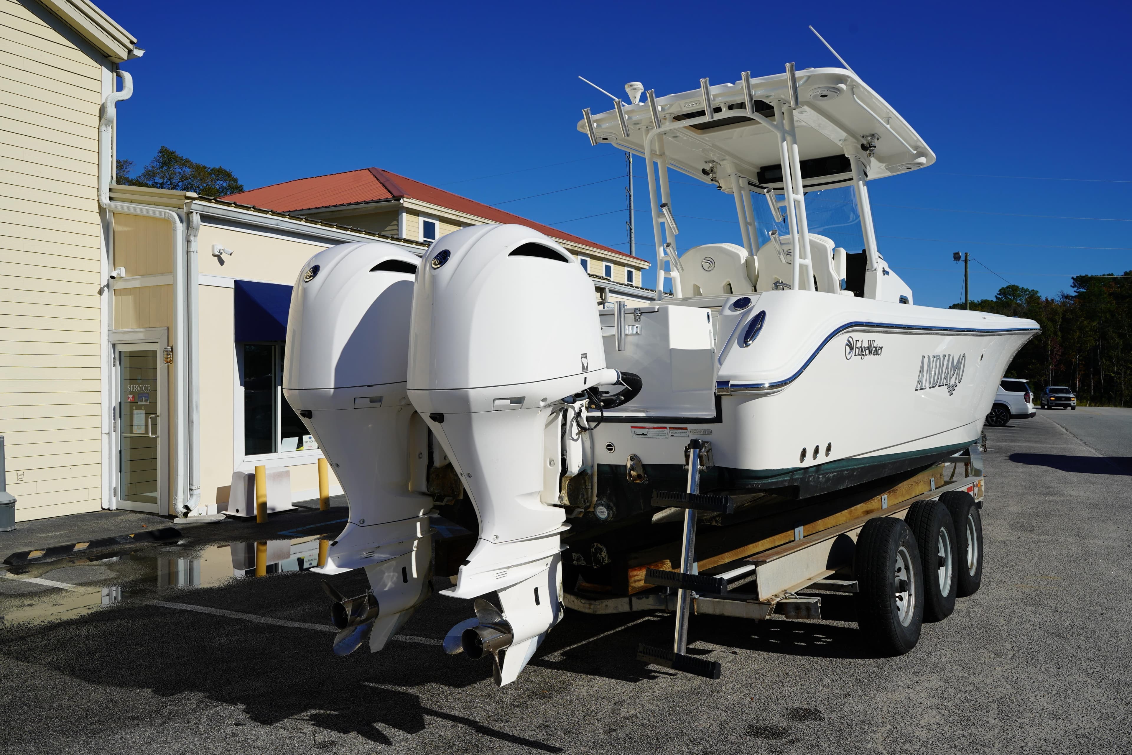 2021 Edgewater 320CC boat on trailer with dual outboard engines, parked near a building.
