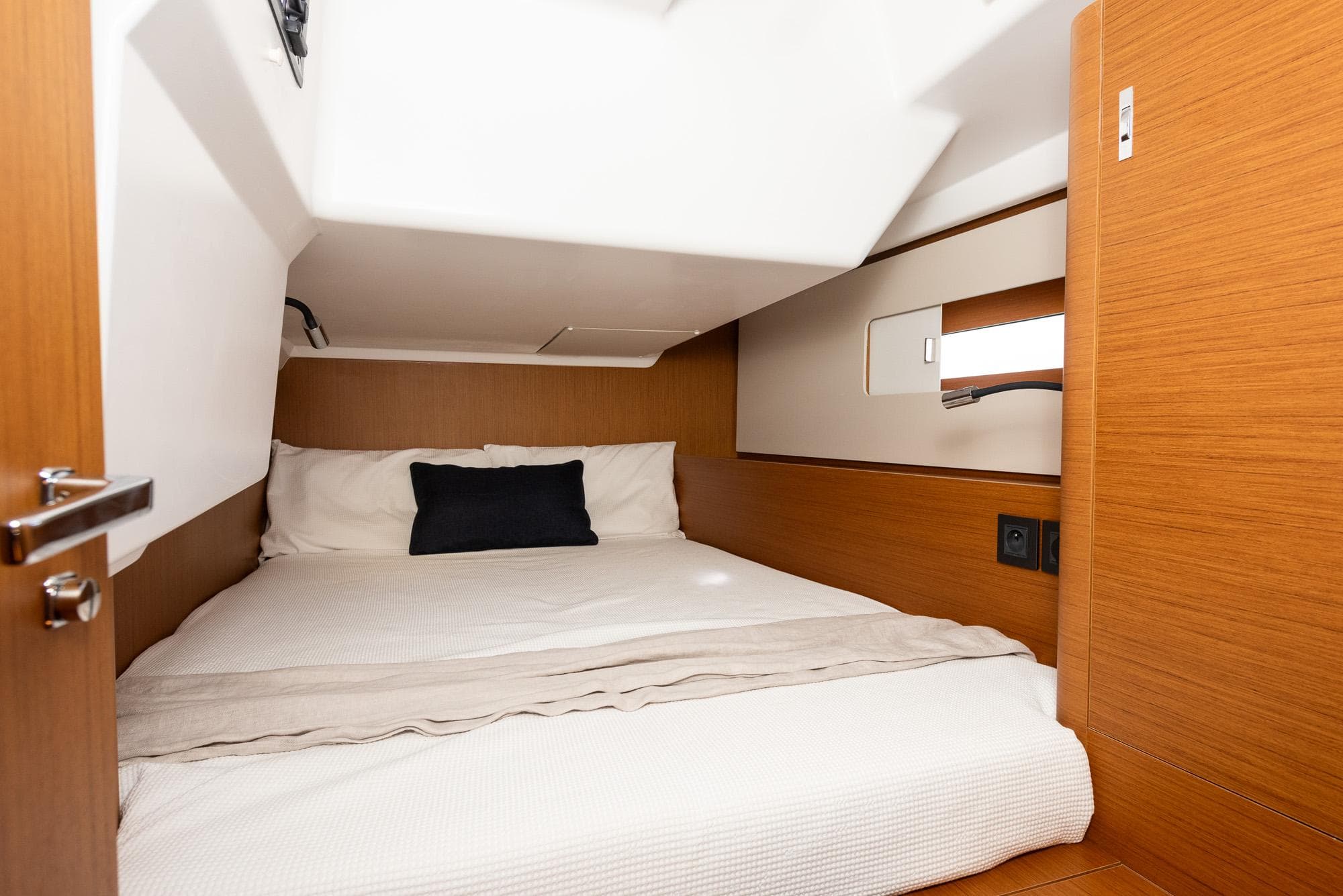 Cozy cabin interior of 2024 Beneteau First 44 yacht with wooden finish and comfortable bedding.